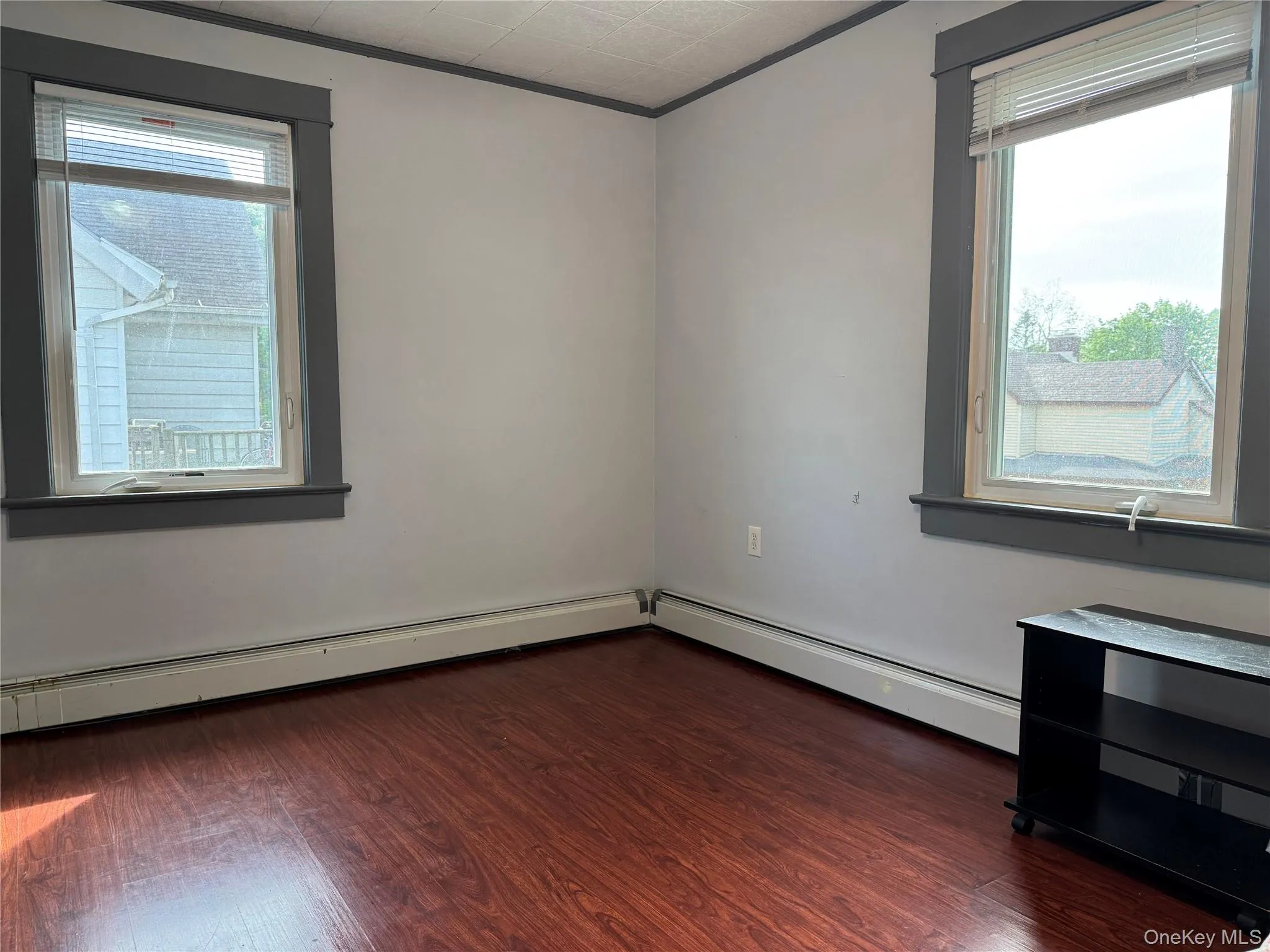 Unfurnished room with dark wood-type flooring, a baseboard radiator, and ornamental molding Unfurnished room with dark wood-type flooring, a baseboard radiator, and ornamental molding