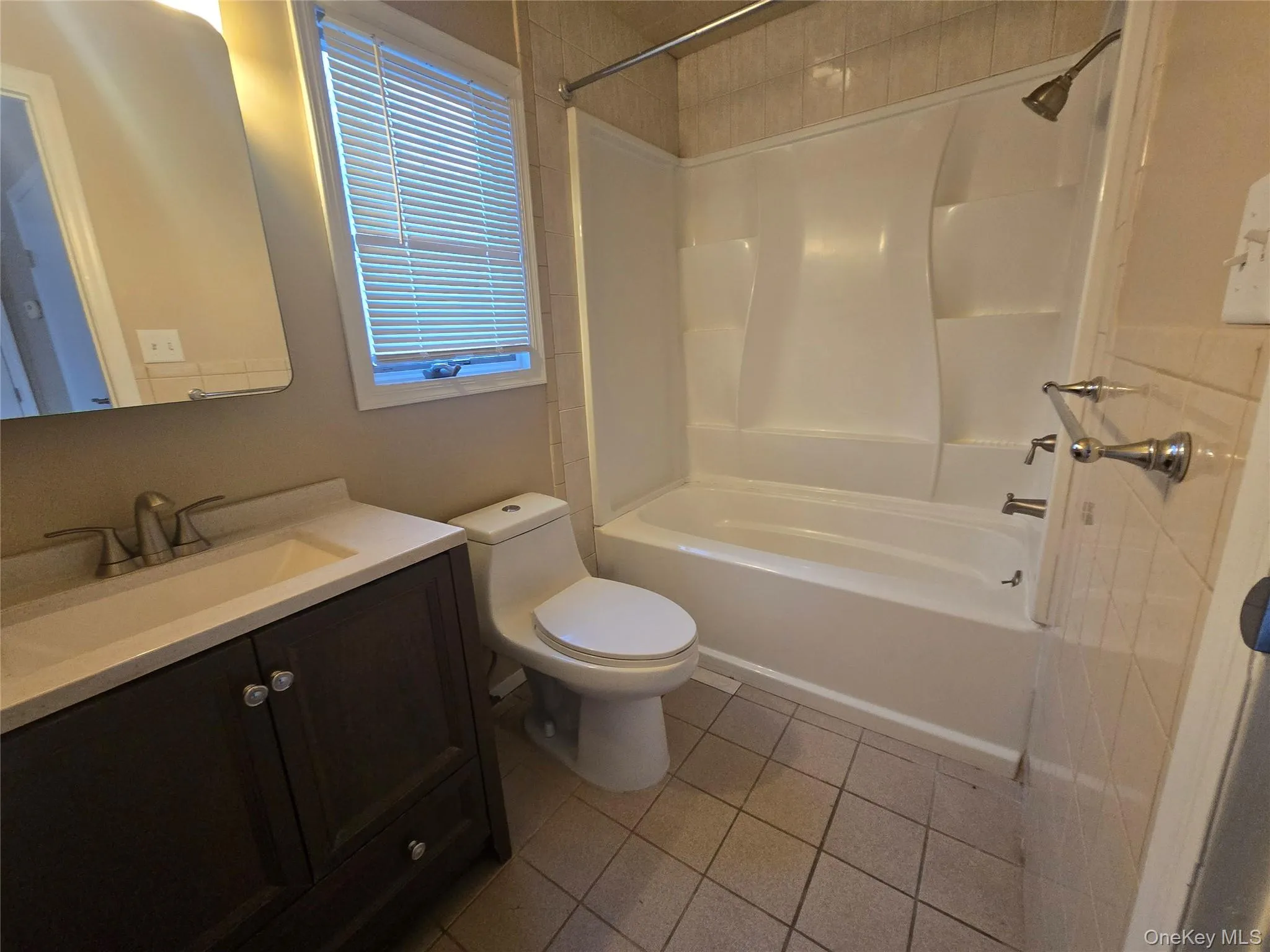 Full bathroom with light tile patterned floors, vanity, and shower / tub combination Full bathroom with light tile patterned floors, vanity, and shower / tub combination