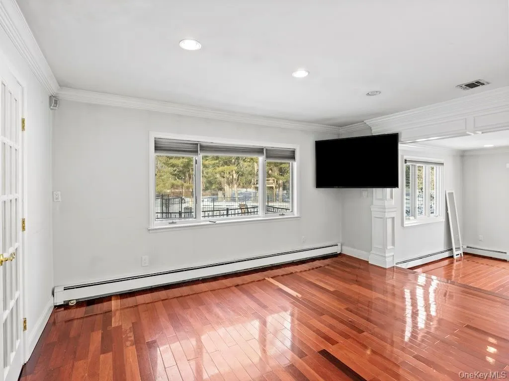 A bi-level ensuite primary bedroom boasts a wood floor and is adorned with numerous windows that overlook a private yard. The additional 11x12 space can be utilized as a gym or office A bi-level ensuite primary bedroom boasts a wood floor and is adorned with numerous windows that overlook a private yard. The additional 11x12 space can be utilized as a gym or office