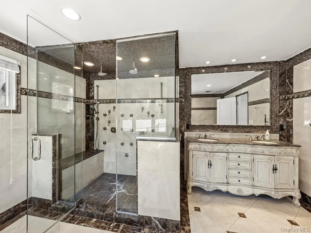 A spacious 11x14 full bathroom features a dual-person walk-in shower equipped with multiple shower jets and a rain showerhead. Additionally, the bathroom includes a double sink. A spacious 11x14 full bathroom features a dual-person walk-in shower equipped with multiple shower jets and a rain showerhead. Additionally, the bathroom includes a double sink.