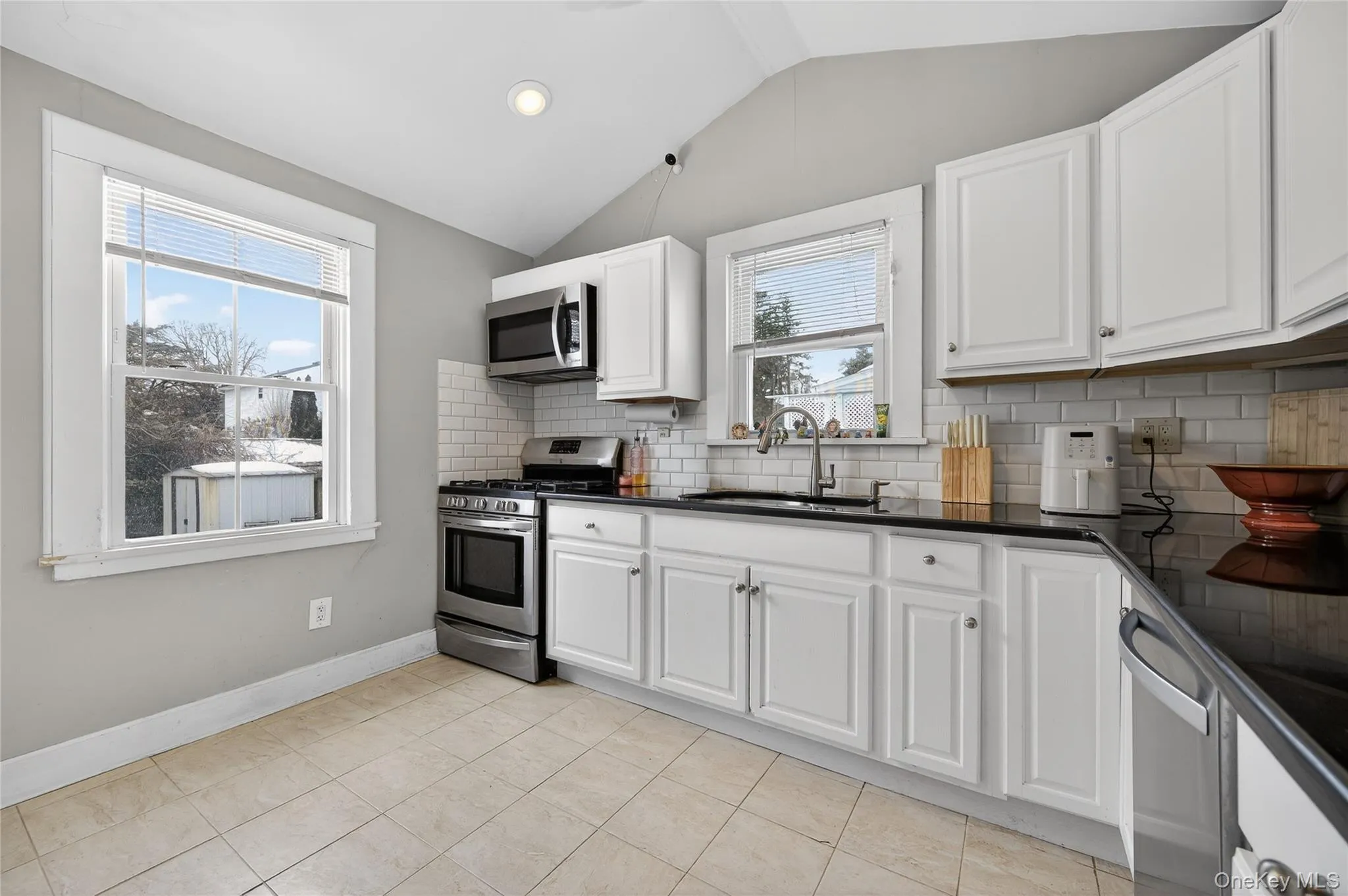 White cabinetry with black granite countertops and subway tile backsplash. Views of the side and backyard. White cabinetry with black granite countertops and subway tile backsplash. Views of the side and backyard.