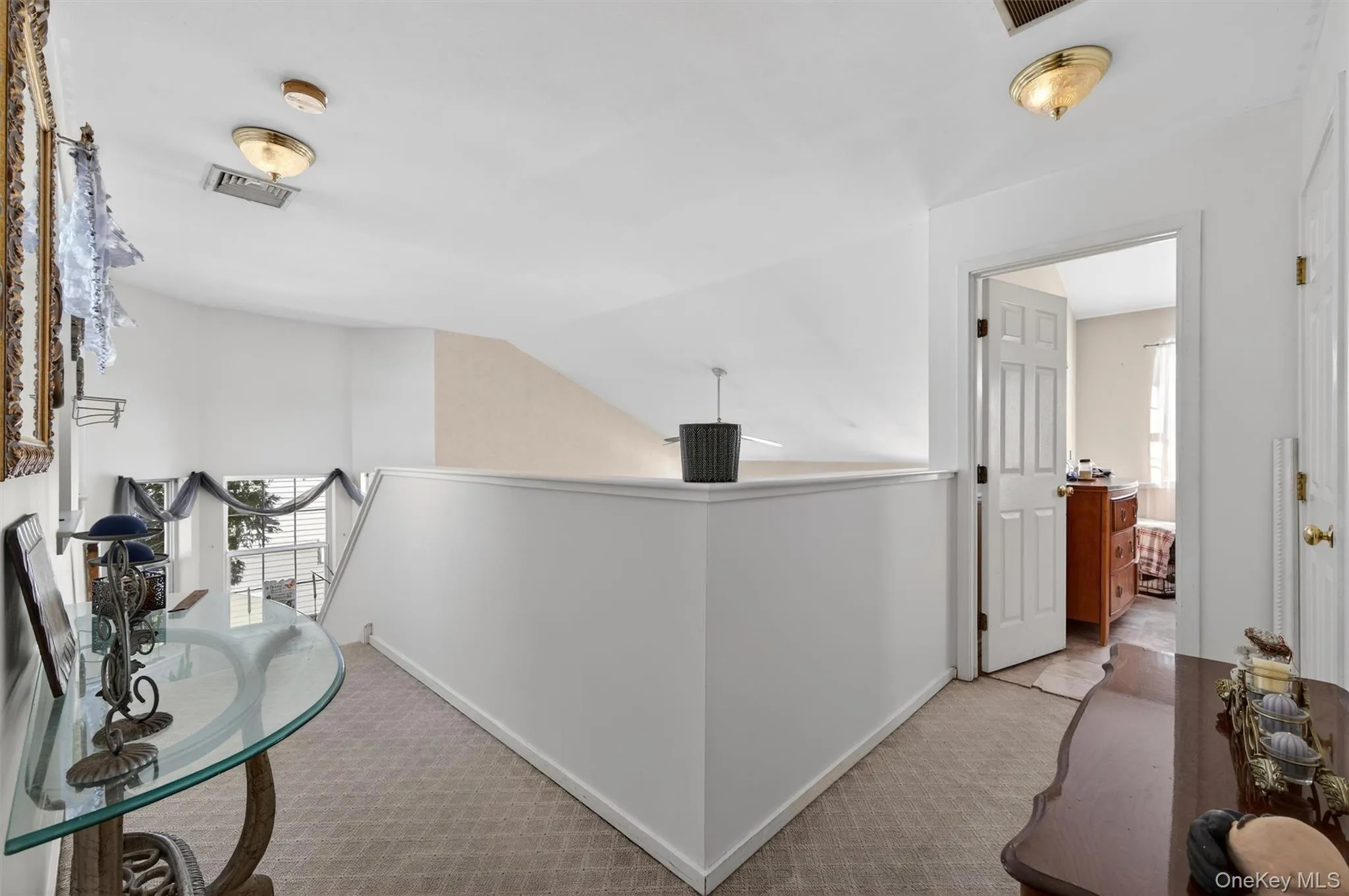 Hall featuring plenty of natural light, carpet floors, and lofted ceiling Hall featuring plenty of natural light, carpet floors, and lofted ceiling
