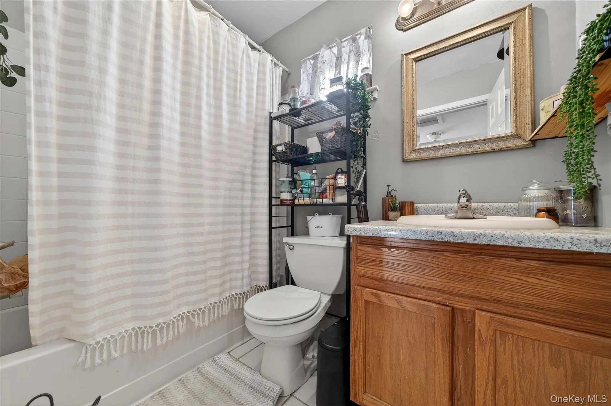 Full bathroom featuring vanity, tile patterned floors, and shower / bath combo with shower curtain Full bathroom featuring vanity, tile patterned floors, and shower / bath combo with shower curtain
