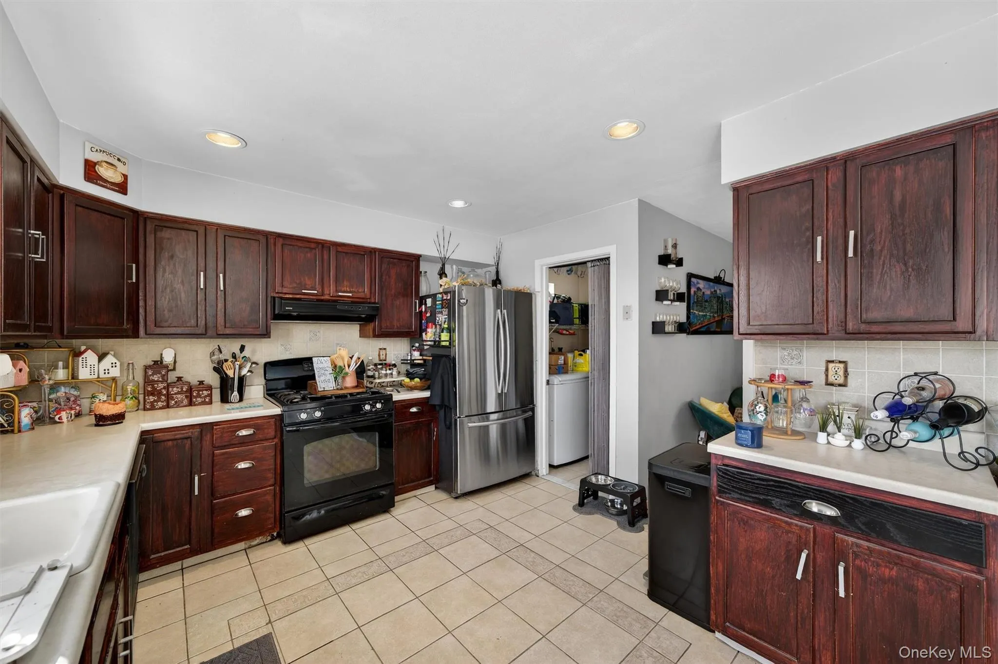 Kitchen featuring black gas range, light countertops, freestanding refrigerator, dark wood finish cabinets, and recessed lighting Kitchen featuring black gas range, light countertops, freestanding refrigerator, dark wood finish cabinets, and recessed lighting