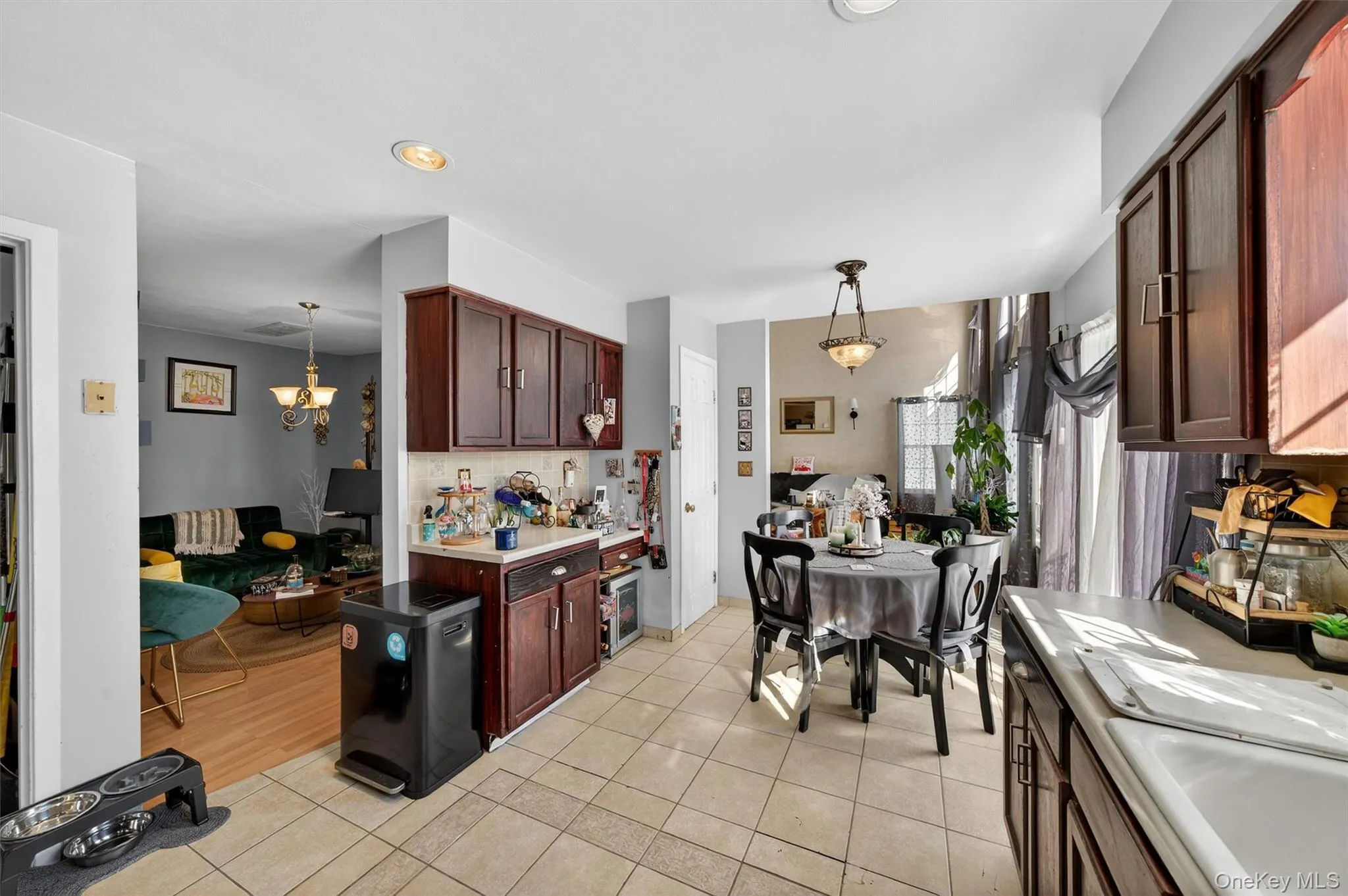 Kitchen with light countertops, dark wood finish cabinets, light tile patterned floors, and suspended lighting Kitchen with light countertops, dark wood finish cabinets, light tile patterned floors, and suspended lighting