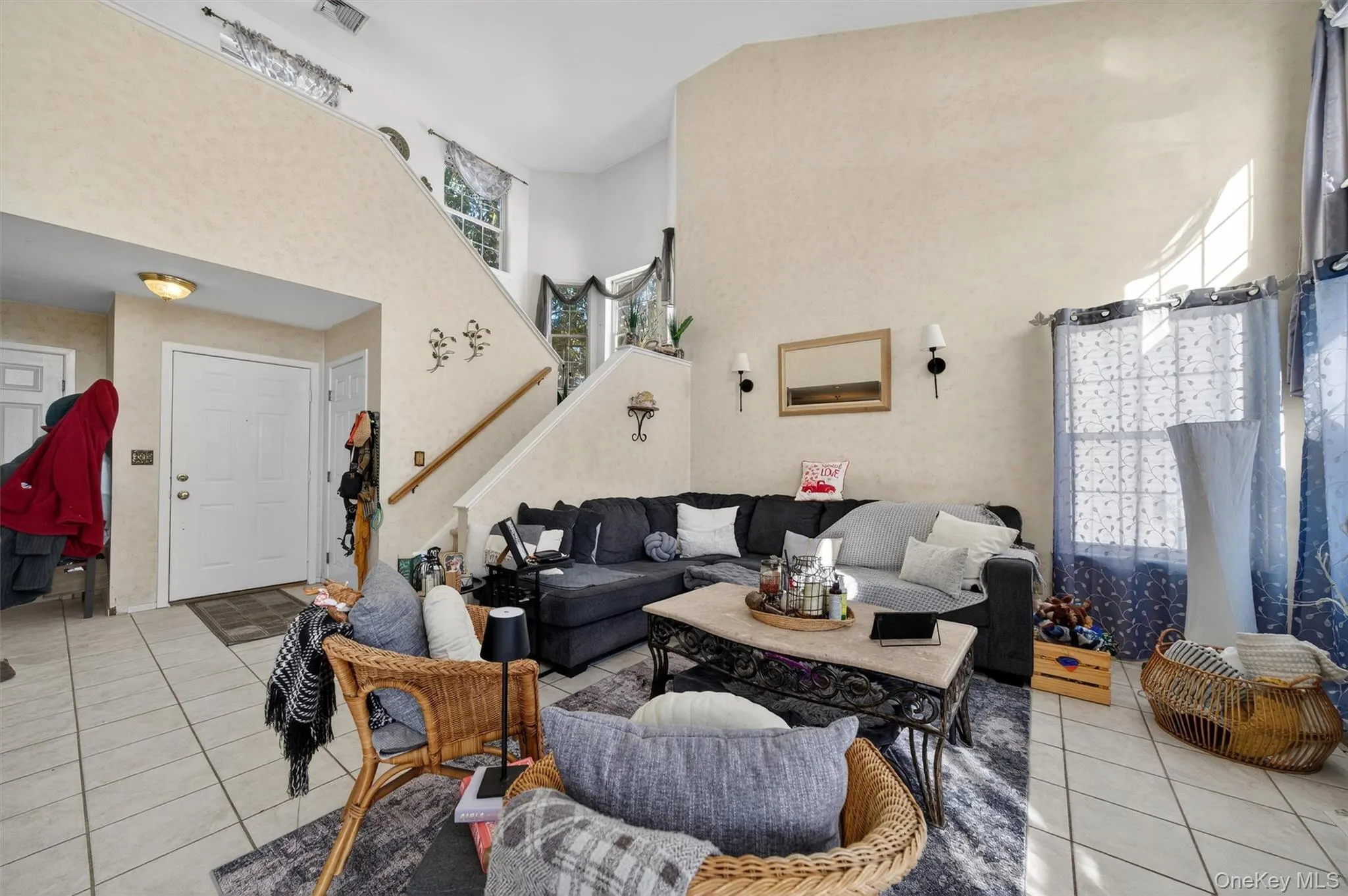 Tiled living area featuring a high ceiling and stairway Tiled living area featuring a high ceiling and stairway