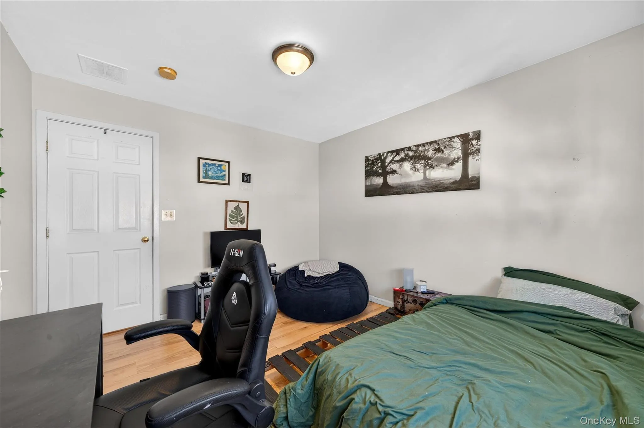 Bedroom featuring wood finished floors and a desk Bedroom featuring wood finished floors and a desk