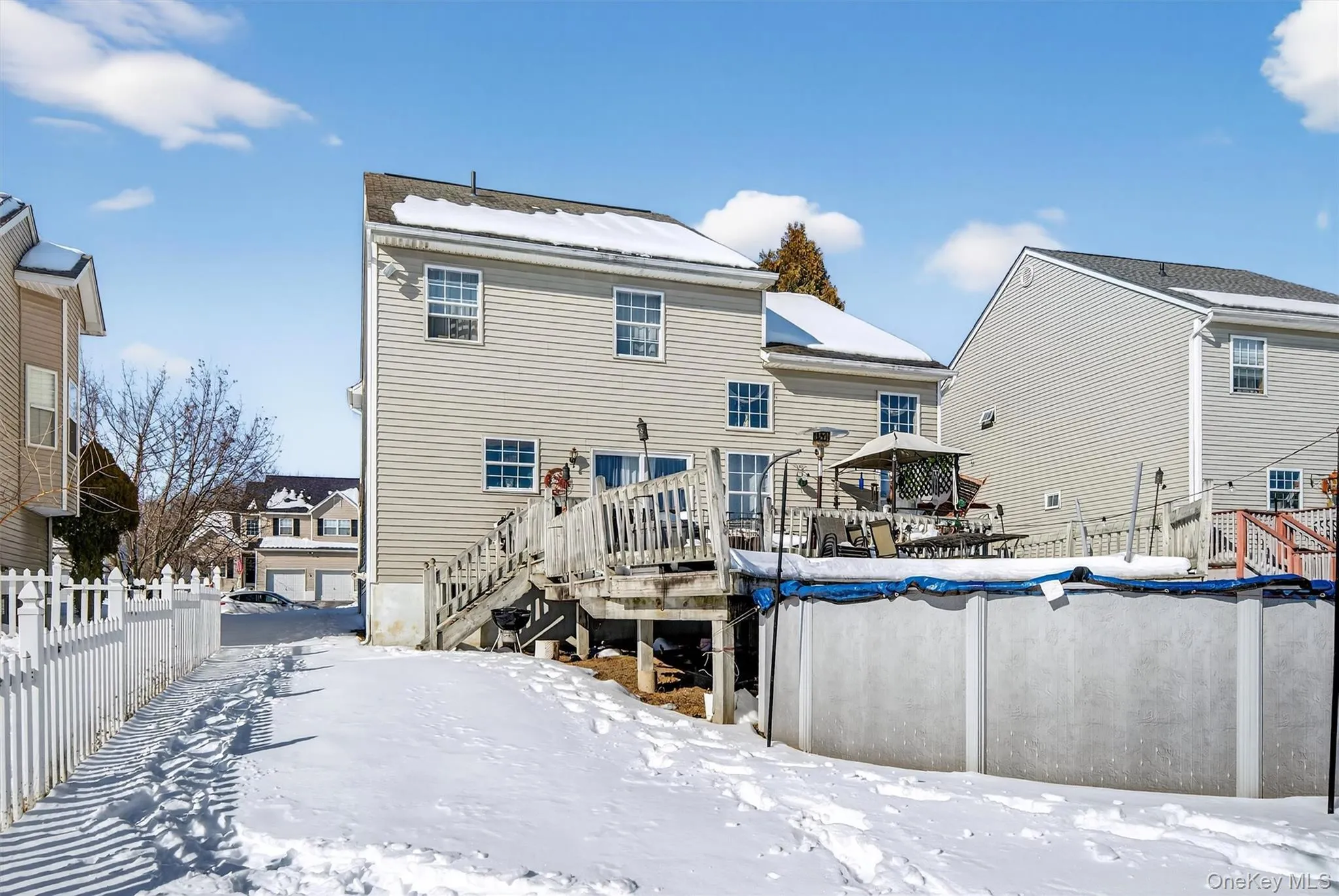 Snow covered rear of property with a wooden deck and stairs Snow covered rear of property with a wooden deck and stairs