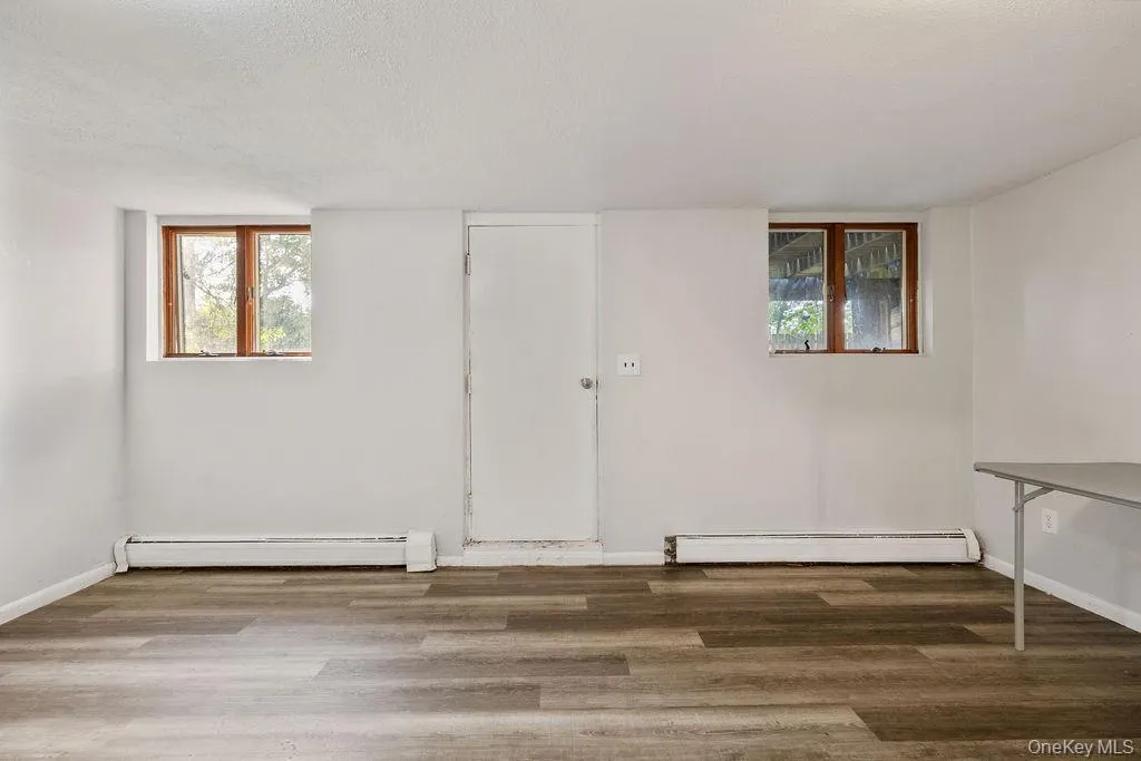 Spare room featuring wood finished floors, a baseboard heating unit, and a textured ceiling Spare room featuring wood finished floors, a baseboard heating unit, and a textured ceiling