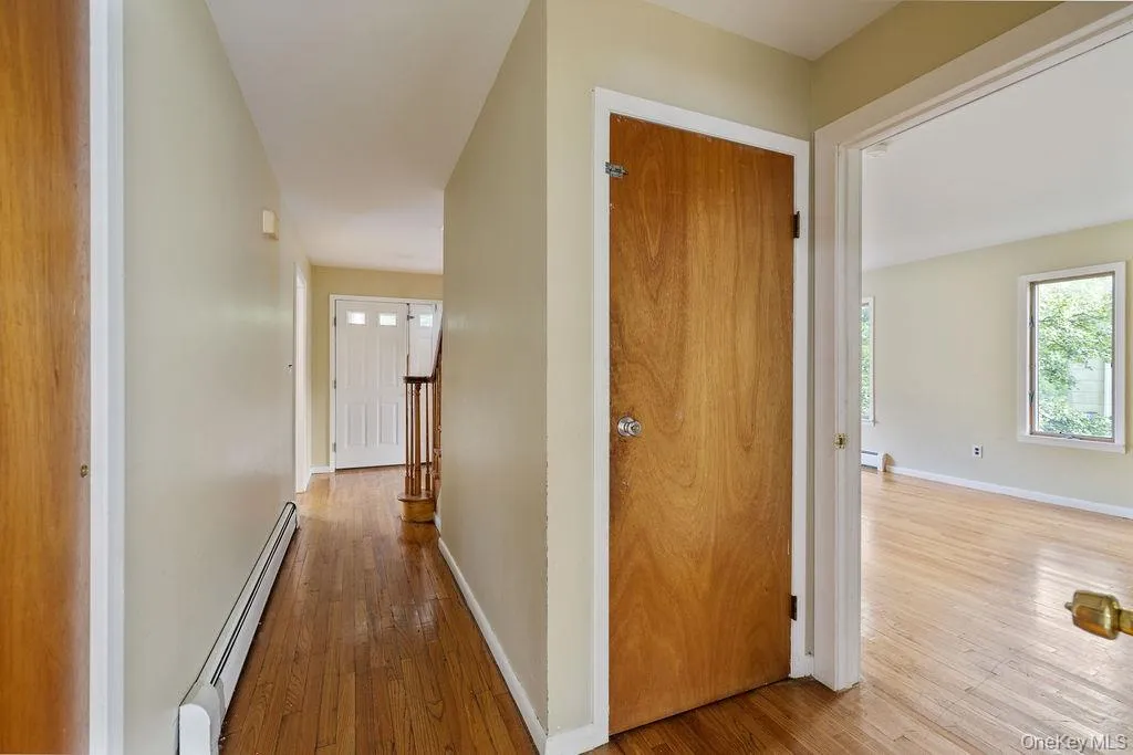 Corridor featuring a baseboard heating unit, hardwood / wood-style floors, and baseboard heating Corridor featuring a baseboard heating unit, hardwood / wood-style floors, and baseboard heating