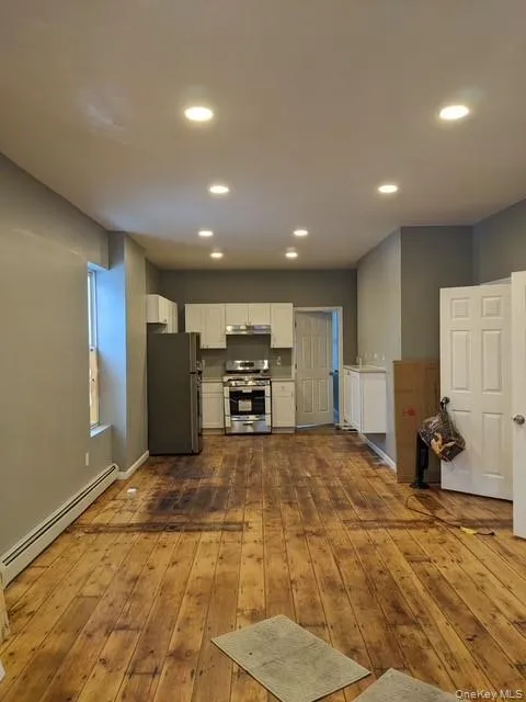 Kitchen featuring baseboard heating, white cabinets, stainless steel appliances, recessed lighting, and dark wood finished floors Kitchen featuring baseboard heating, white cabinets, stainless steel appliances, recessed lighting, and dark wood finished floors