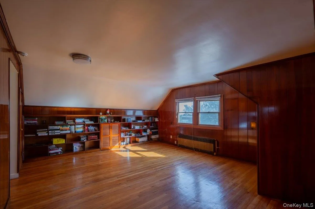Office space with radiator, wooden walls, lofted ceiling, and wood finished floors Office space with radiator, wooden walls, lofted ceiling, and wood finished floors