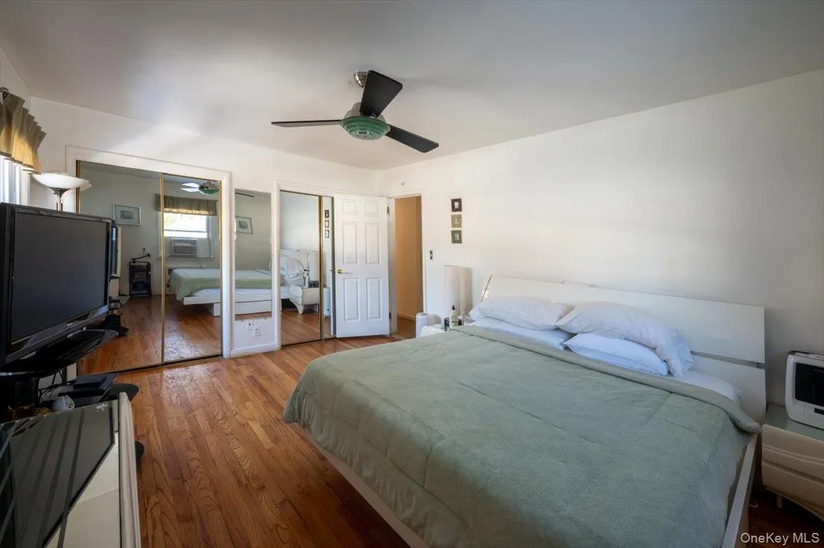 Bedroom with multiple closets, wood finished floors, cooling unit, and ceiling fan Bedroom with multiple closets, wood finished floors, cooling unit, and ceiling fan