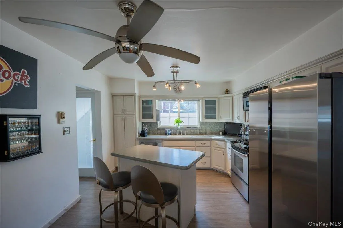 Kitchen featuring stainless steel appliances, tasteful backsplash, a kitchen island, a kitchen breakfast bar, and wood finished floors Kitchen featuring stainless steel appliances, tasteful backsplash, a kitchen island, a kitchen breakfast bar, and wood finished floors