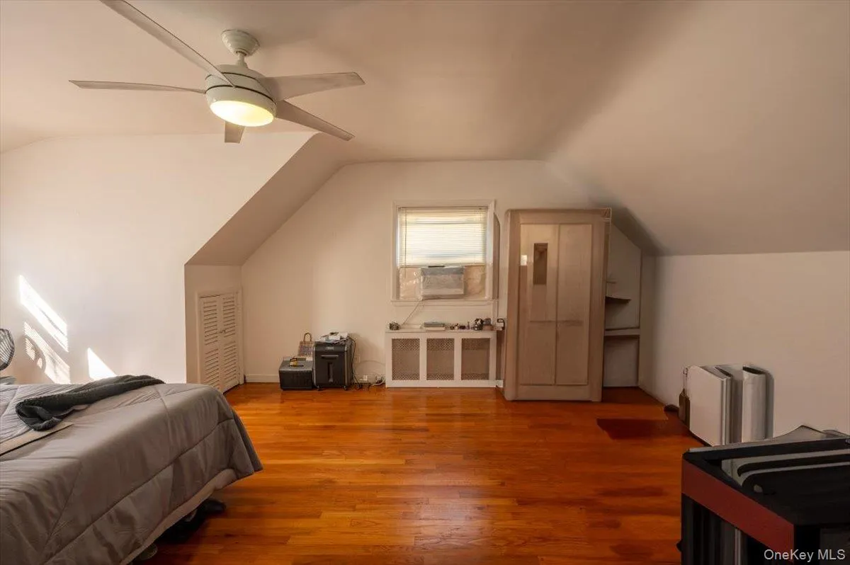 Bedroom with vaulted ceiling, wood finished floors, cooling unit, and ceiling fan Bedroom with vaulted ceiling, wood finished floors, cooling unit, and ceiling fan