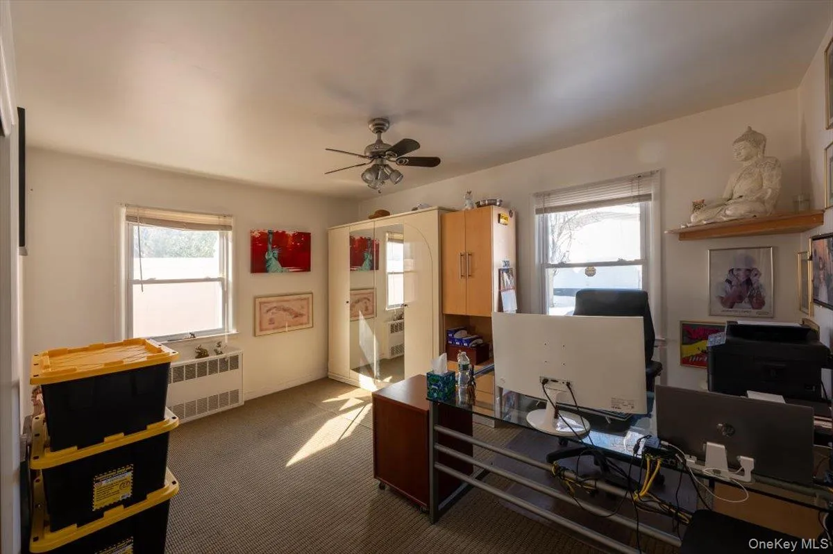 Home office featuring radiator, a ceiling fan, and carpet flooring Home office featuring radiator, a ceiling fan, and carpet flooring