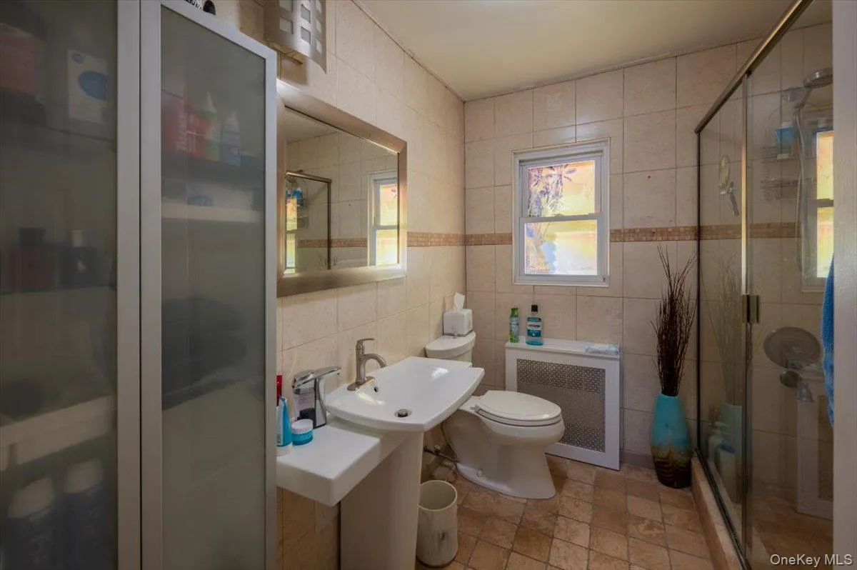 Bathroom featuring radiator heating unit, tile walls, and a stall shower Bathroom featuring radiator heating unit, tile walls, and a stall shower