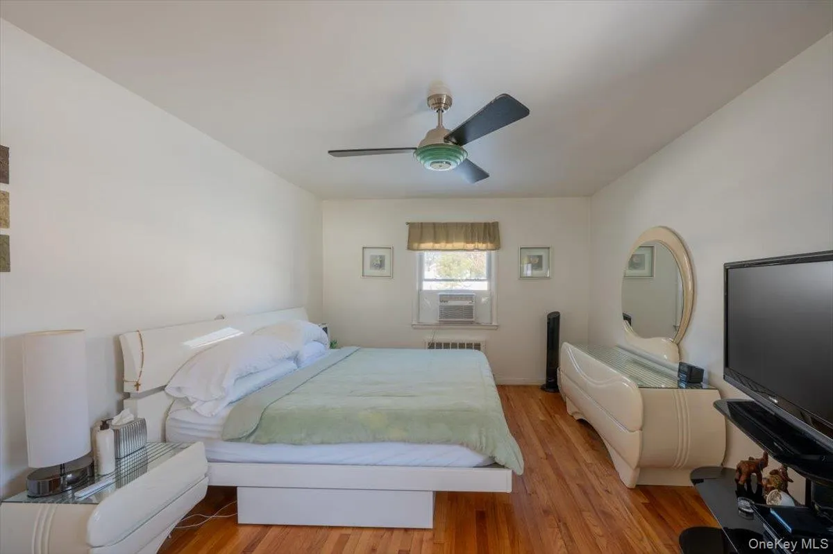 Bedroom with cooling unit, wood finished floors, ceiling fan, and radiator heating unit Bedroom with cooling unit, wood finished floors, ceiling fan, and radiator heating unit