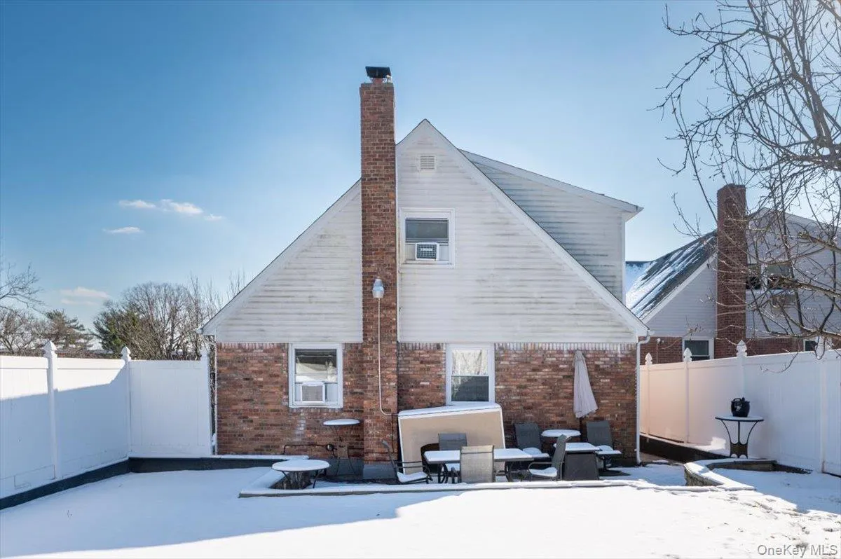Snow covered property featuring a fenced backyard, brick siding, and a chimney Snow covered property featuring a fenced backyard, brick siding, and a chimney