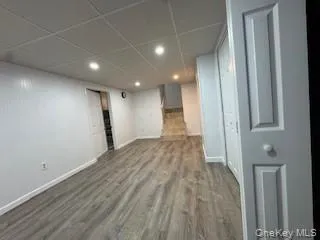 Finished basement featuring a paneled ceiling, baseboards, and wood finished floors Finished basement featuring a paneled ceiling, baseboards, and wood finished floors