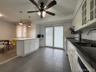 Kitchen featuring glass insert cabinets, dishwasher, electric range oven, a ceiling fan, and a sink Kitchen featuring glass insert cabinets, dishwasher, electric range oven, a ceiling fan, and a sink