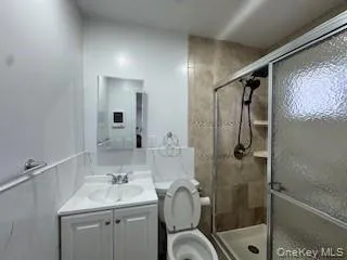 Full bathroom featuring vanity, tile walls, toilet, and a stall shower Full bathroom featuring vanity, tile walls, toilet, and a stall shower