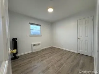 Spare room with baseboards, wood finished floors, and radiator heating unit Spare room with baseboards, wood finished floors, and radiator heating unit