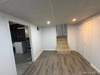 Finished below grade area featuring stairs, a paneled ceiling, baseboards, and wood finished floors Finished below grade area featuring stairs, a paneled ceiling, baseboards, and wood finished floors