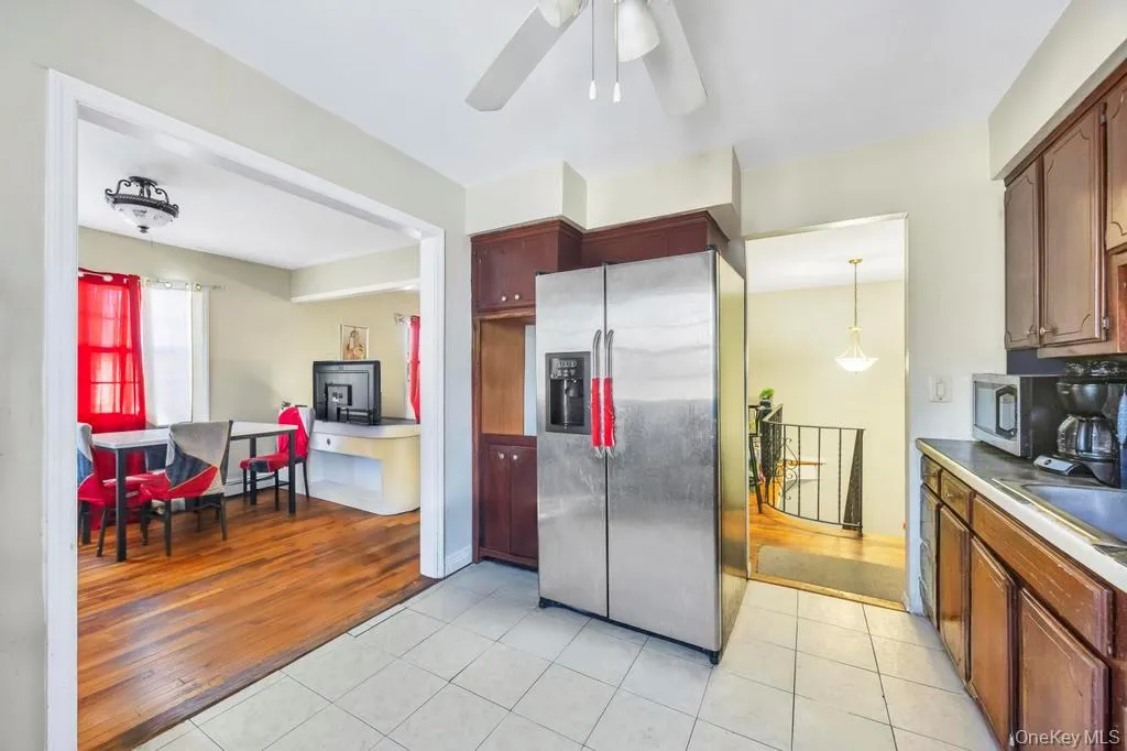 Kitchen with stainless steel appliances, light tile patterned floors, hanging light fixtures, a ceiling fan, and light countertops Kitchen with stainless steel appliances, light tile patterned floors, hanging light fixtures, a ceiling fan, and light countertops