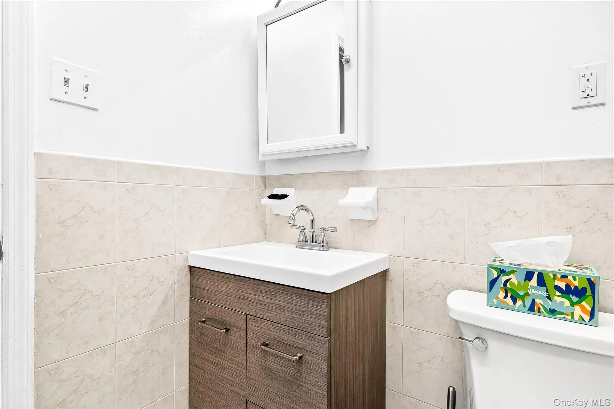 Bathroom with vanity, tile walls, and wainscoting Bathroom with vanity, tile walls, and wainscoting