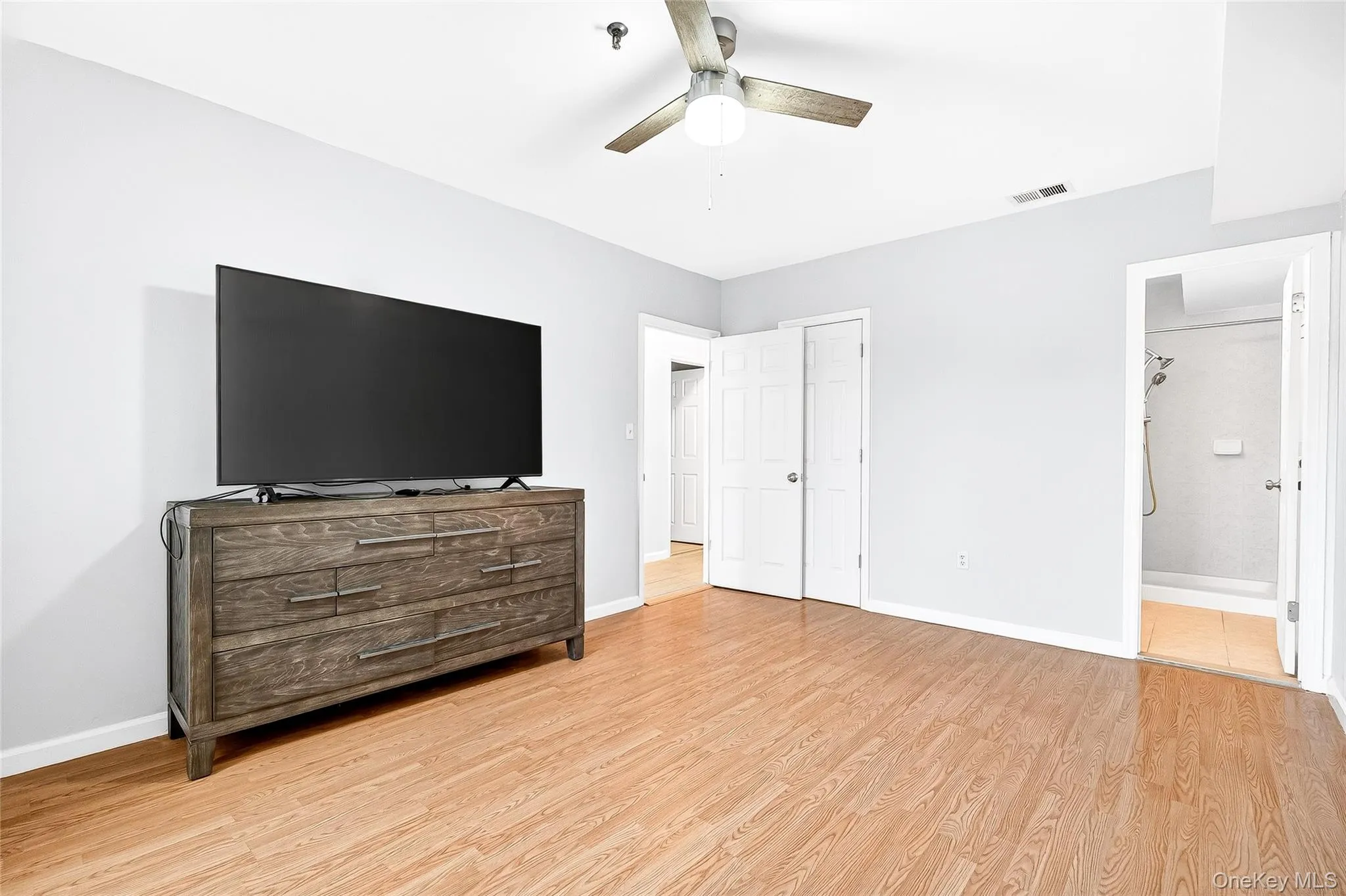 Unfurnished second primary bedroom with light wood finished floors, ceiling fan, and ensuite bathroom Unfurnished second primary bedroom with light wood finished floors, ceiling fan, and ensuite bathroom