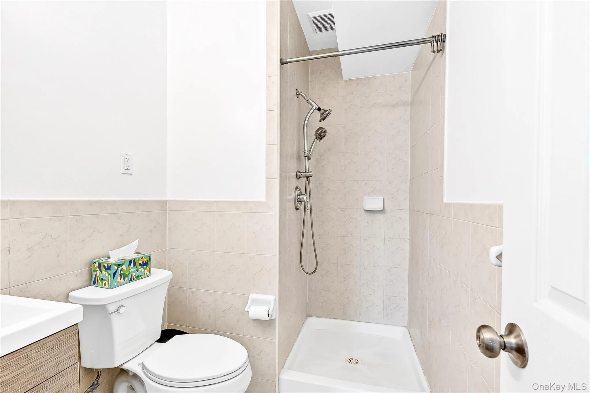 Primary bedroom full bath featuring vanity, a stall shower, and tile walls Primary bedroom full bath featuring vanity, a stall shower, and tile walls