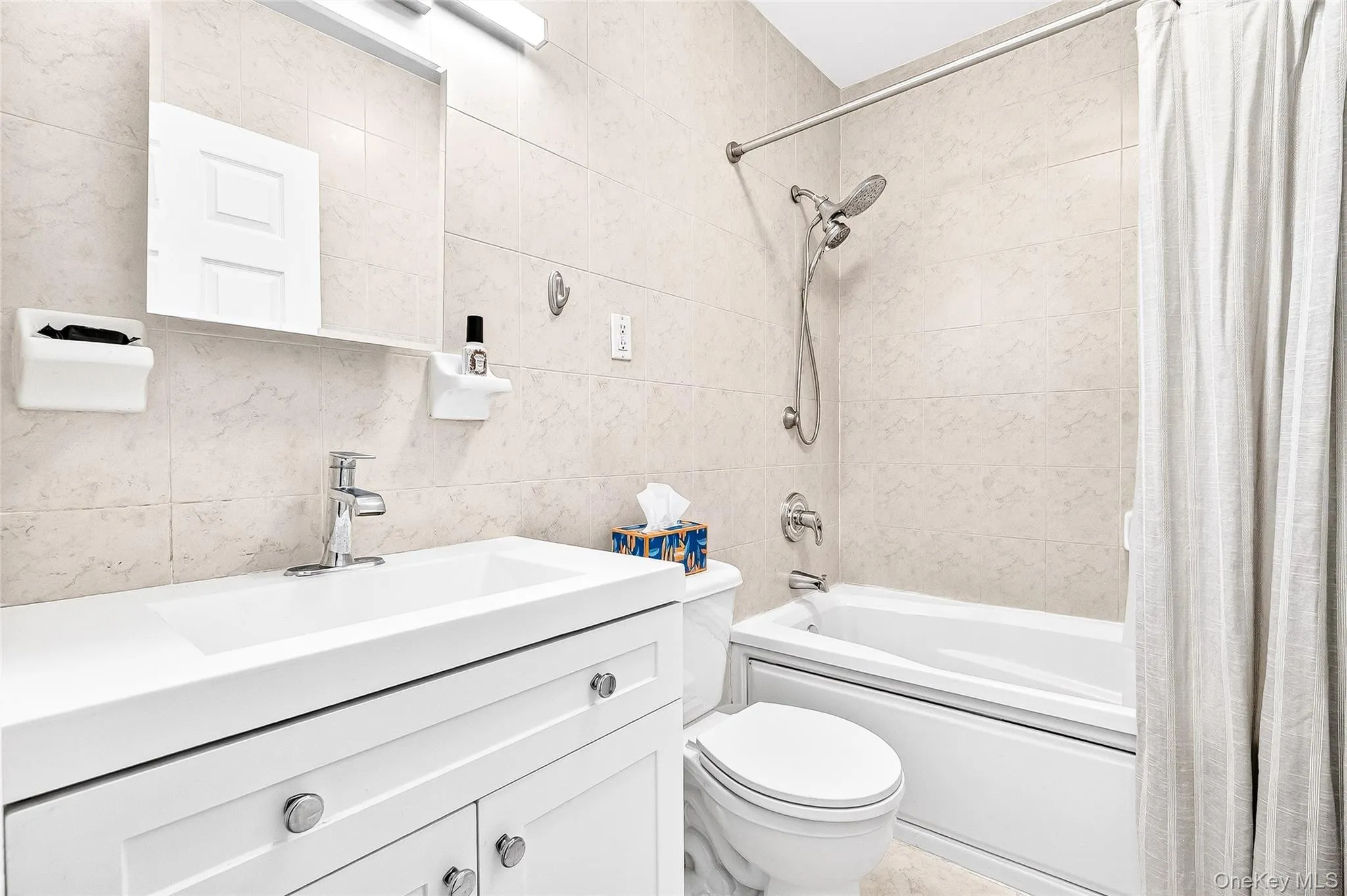 Hallway full bath featuring shower / jacuzzi bath combo, vanity, and tile walls Hallway full bath featuring shower / jacuzzi bath combo, vanity, and tile walls