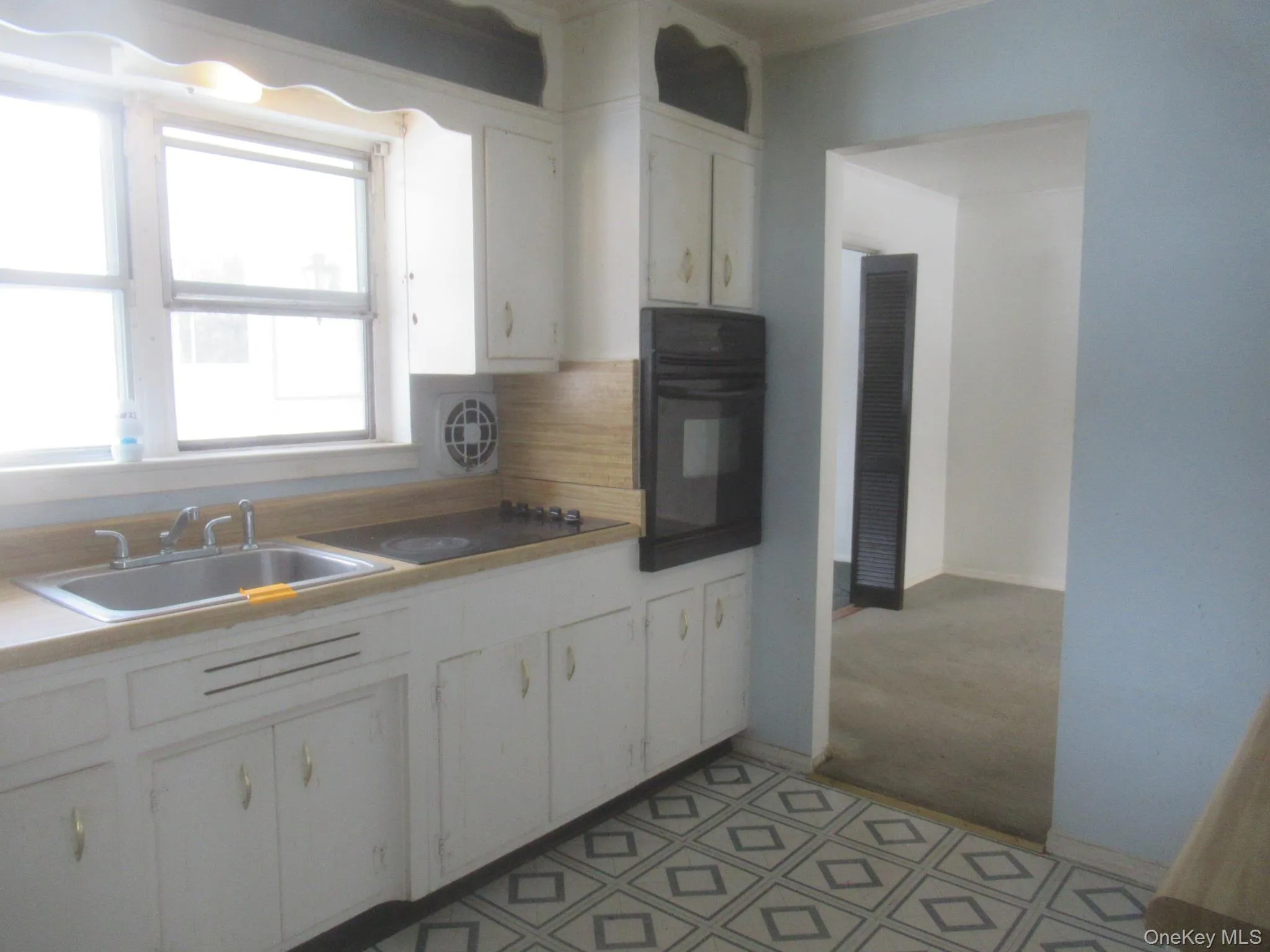 Kitchen featuring white cabinetry, black oven, tasteful backsplash, and light countertops Kitchen featuring white cabinetry, black oven, tasteful backsplash, and light countertops
