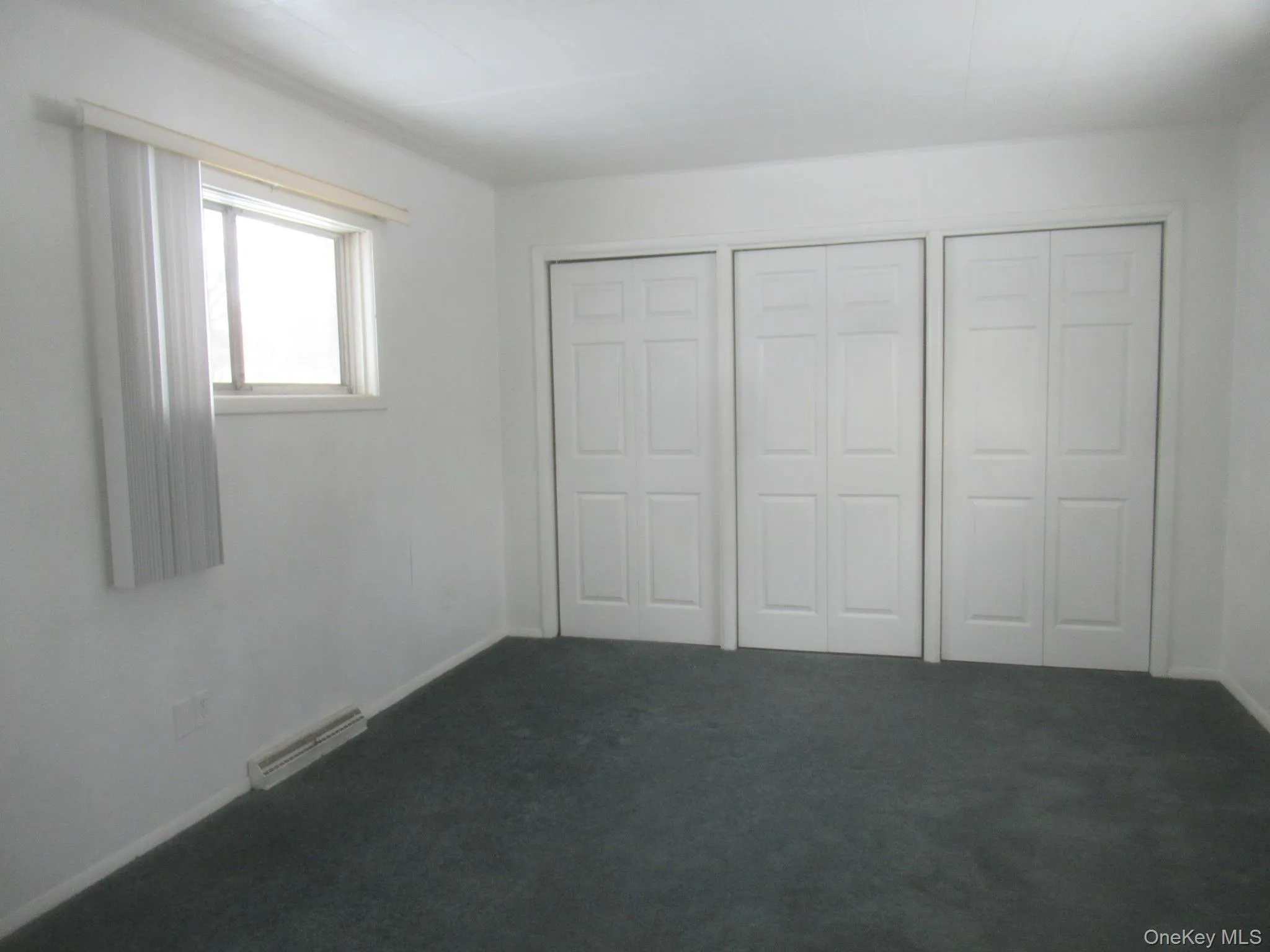Unfurnished bedroom with dark colored carpet and a closet Unfurnished bedroom with dark colored carpet and a closet