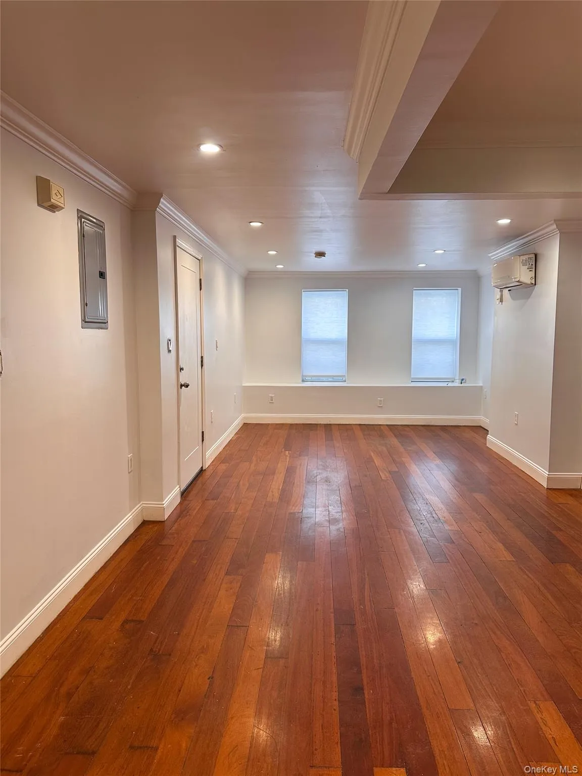 Empty room featuring ornamental molding, dark wood-style flooring, recessed lighting, and electric panel Empty room featuring ornamental molding, dark wood-style flooring, recessed lighting, and electric panel