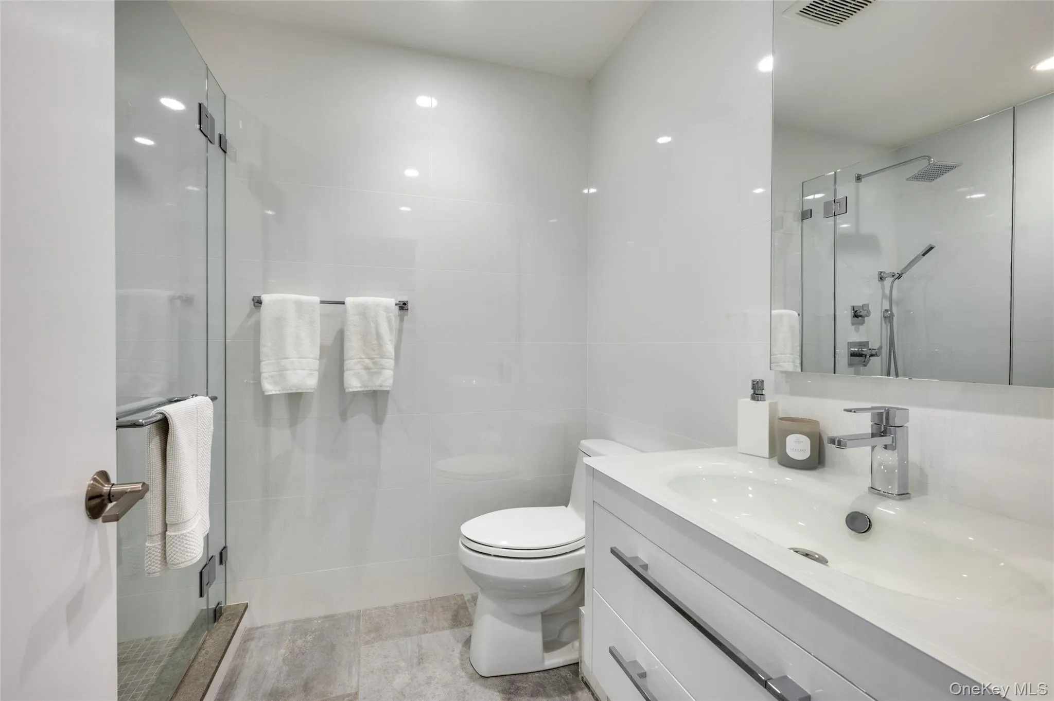 Bathroom with vanity, a shower with shower door, tile walls, and toilet Bathroom with vanity, a shower with shower door, tile walls, and toilet