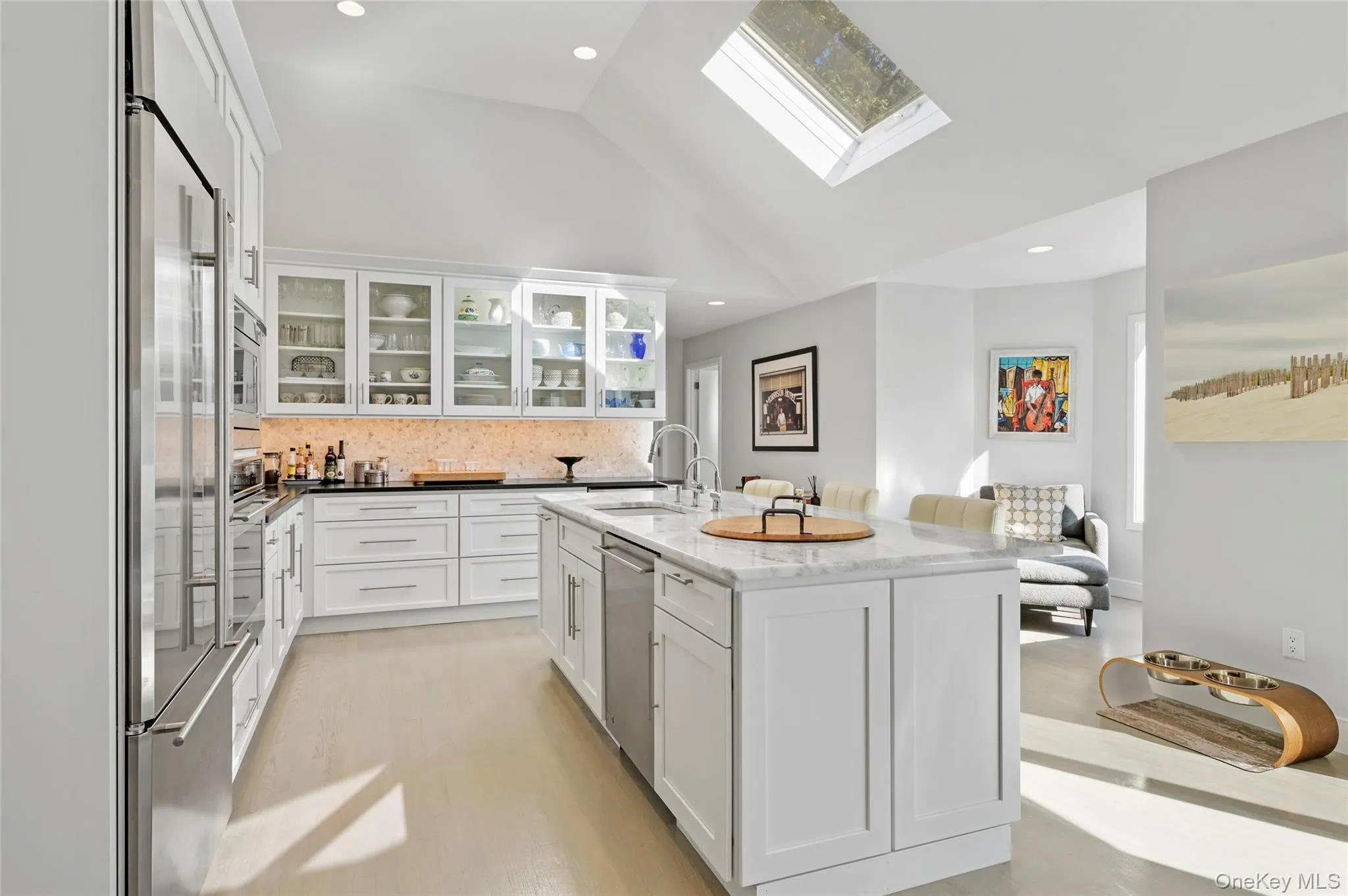 Kitchen with sink, white cabinetry, stainless steel appliances, light stone countertops, and a kitchen island with sink Kitchen with sink, white cabinetry, stainless steel appliances, light stone countertops, and a kitchen island with sink