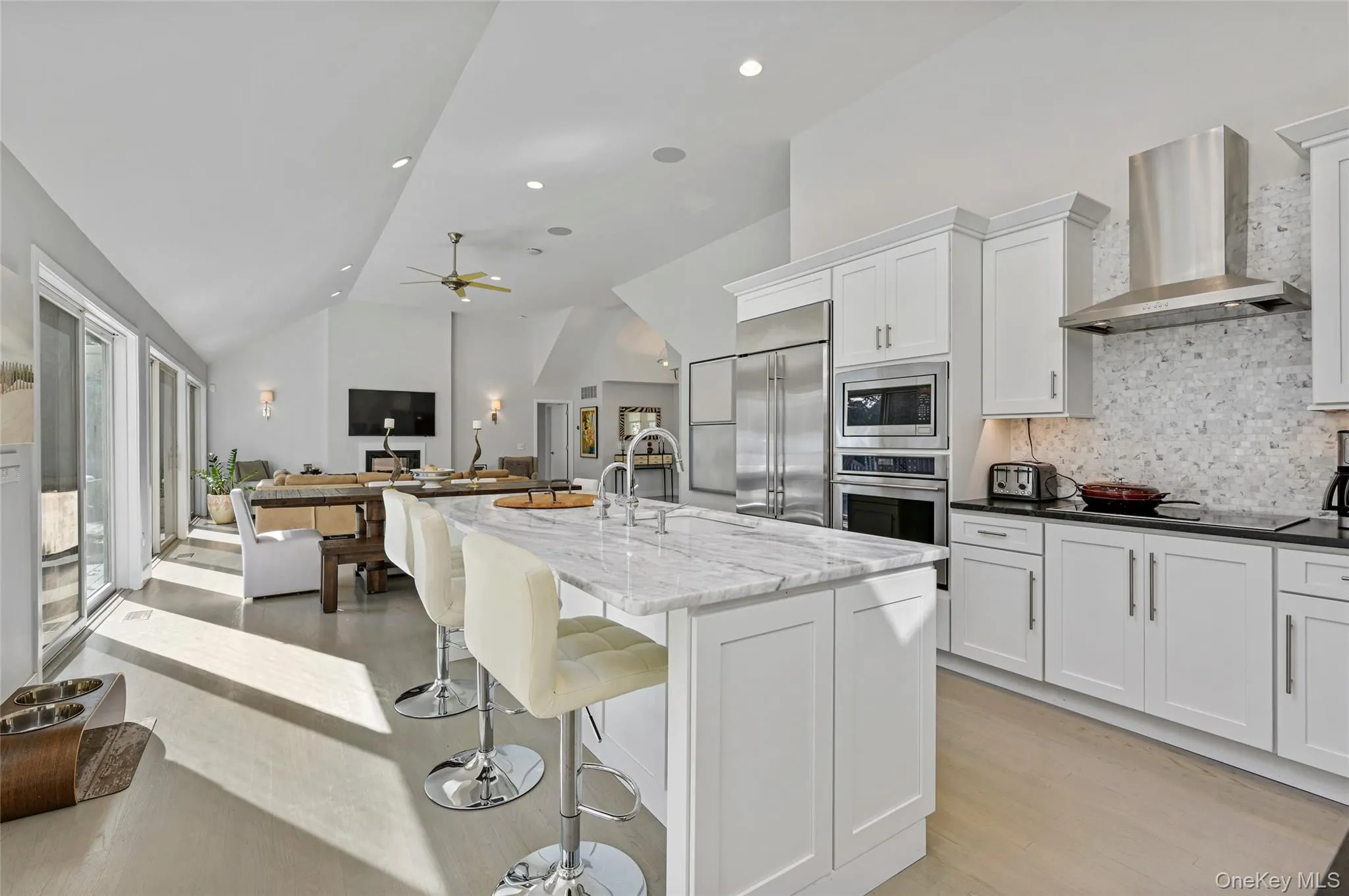 Kitchen featuring sink, dark stone countertops, built in appliances, white cabinets, and wall chimney exhaust hood Kitchen featuring sink, dark stone countertops, built in appliances, white cabinets, and wall chimney exhaust hood