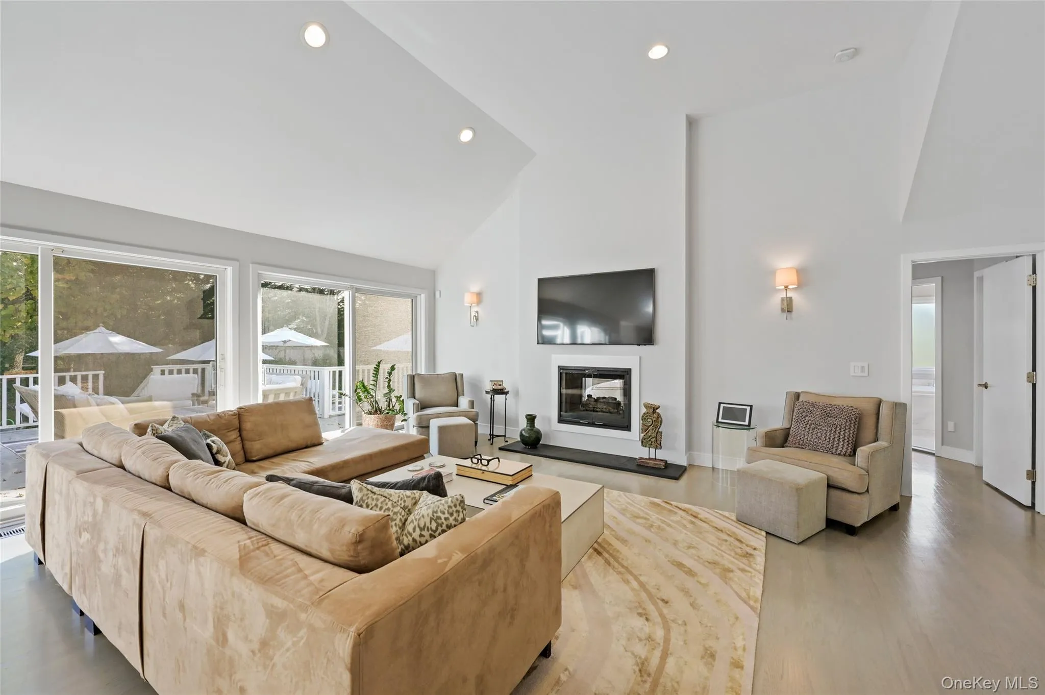 Living room featuring hardwood / wood-style flooring, a wealth of natural light, and high vaulted ceiling Living room featuring hardwood / wood-style flooring, a wealth of natural light, and high vaulted ceiling