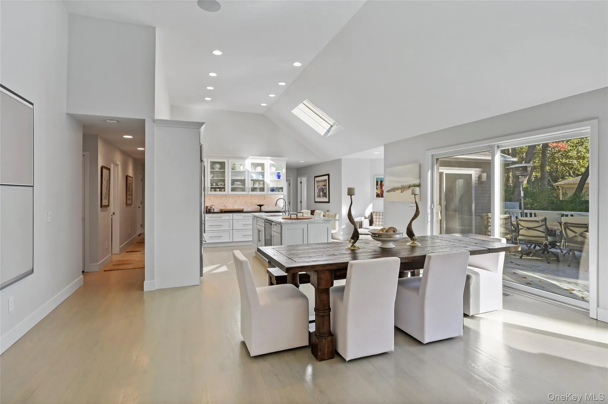 Dining area featuring sink, a skylight, high vaulted ceiling, and light wood-type flooring Dining area featuring sink, a skylight, high vaulted ceiling, and light wood-type flooring