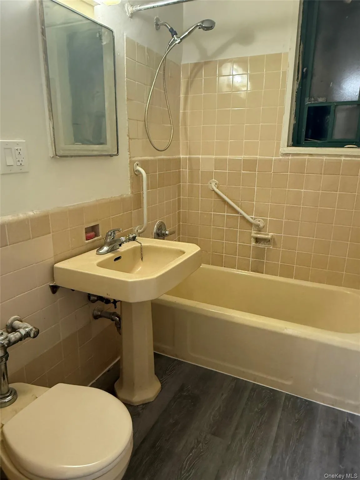 Bathroom with shower combination, tile walls, and dark wood-type flooring Bathroom with shower combination, tile walls, and dark wood-type flooring