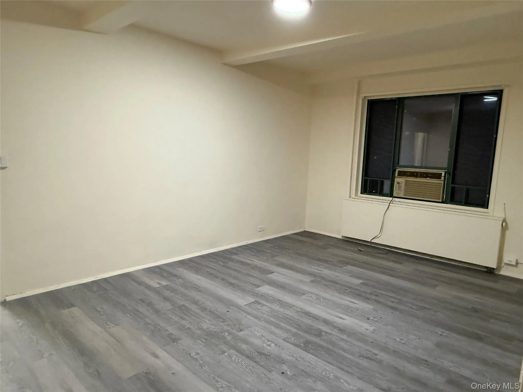 Living room featuring wood finished floors, beamed ceiling, and cooling unit Living room featuring wood finished floors, beamed ceiling, and cooling unit