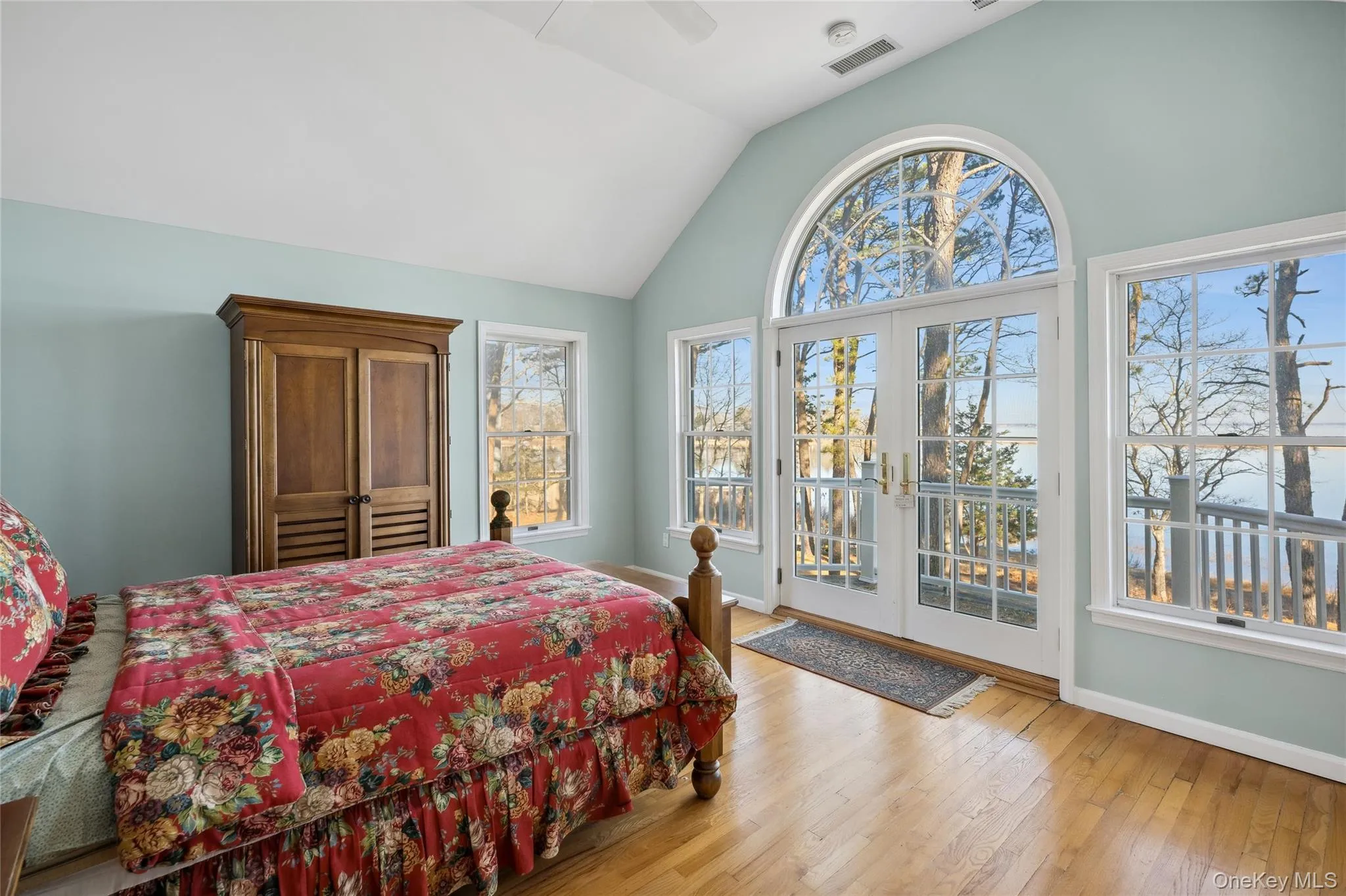 Bedroom featuring lofted ceiling, access to exterior, multiple windows, and visible vents Bedroom featuring lofted ceiling, access to exterior, multiple windows, and visible vents