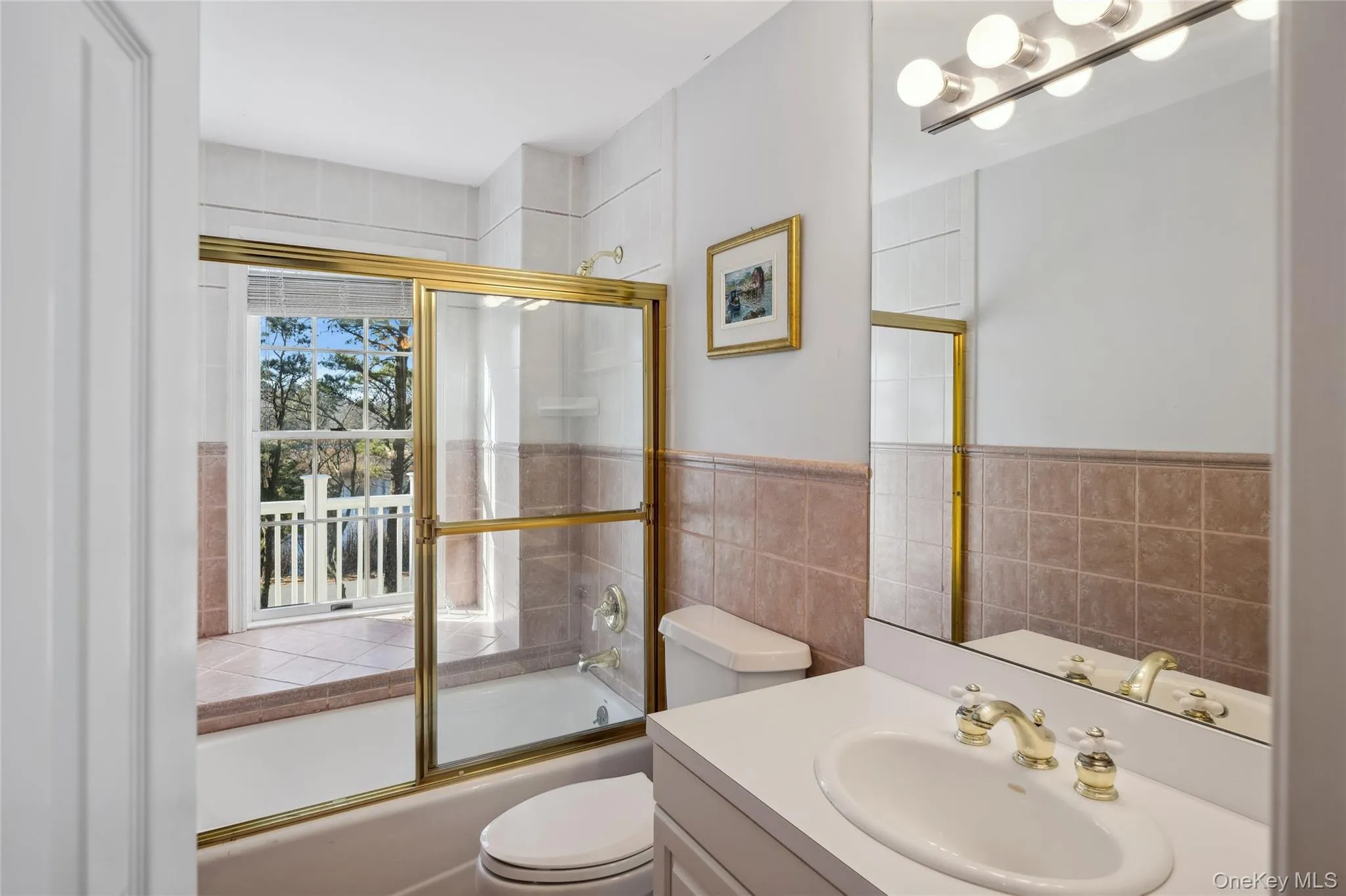 Full bathroom featuring toilet, vanity, shower / bath combination with glass door, and tile walls Full bathroom featuring toilet, vanity, shower / bath combination with glass door, and tile walls