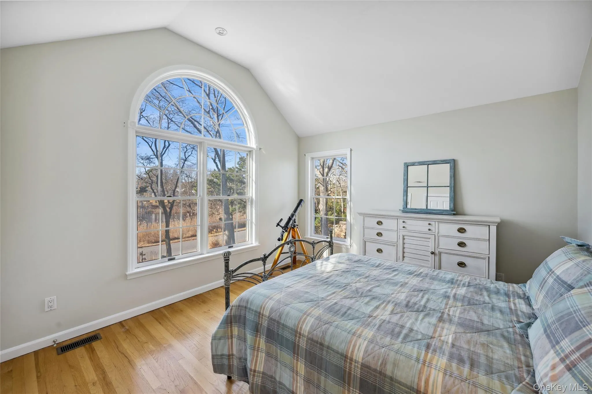 Bedroom with light wood-type flooring, vaulted ceiling, baseboards, and visible vents Bedroom with light wood-type flooring, vaulted ceiling, baseboards, and visible vents