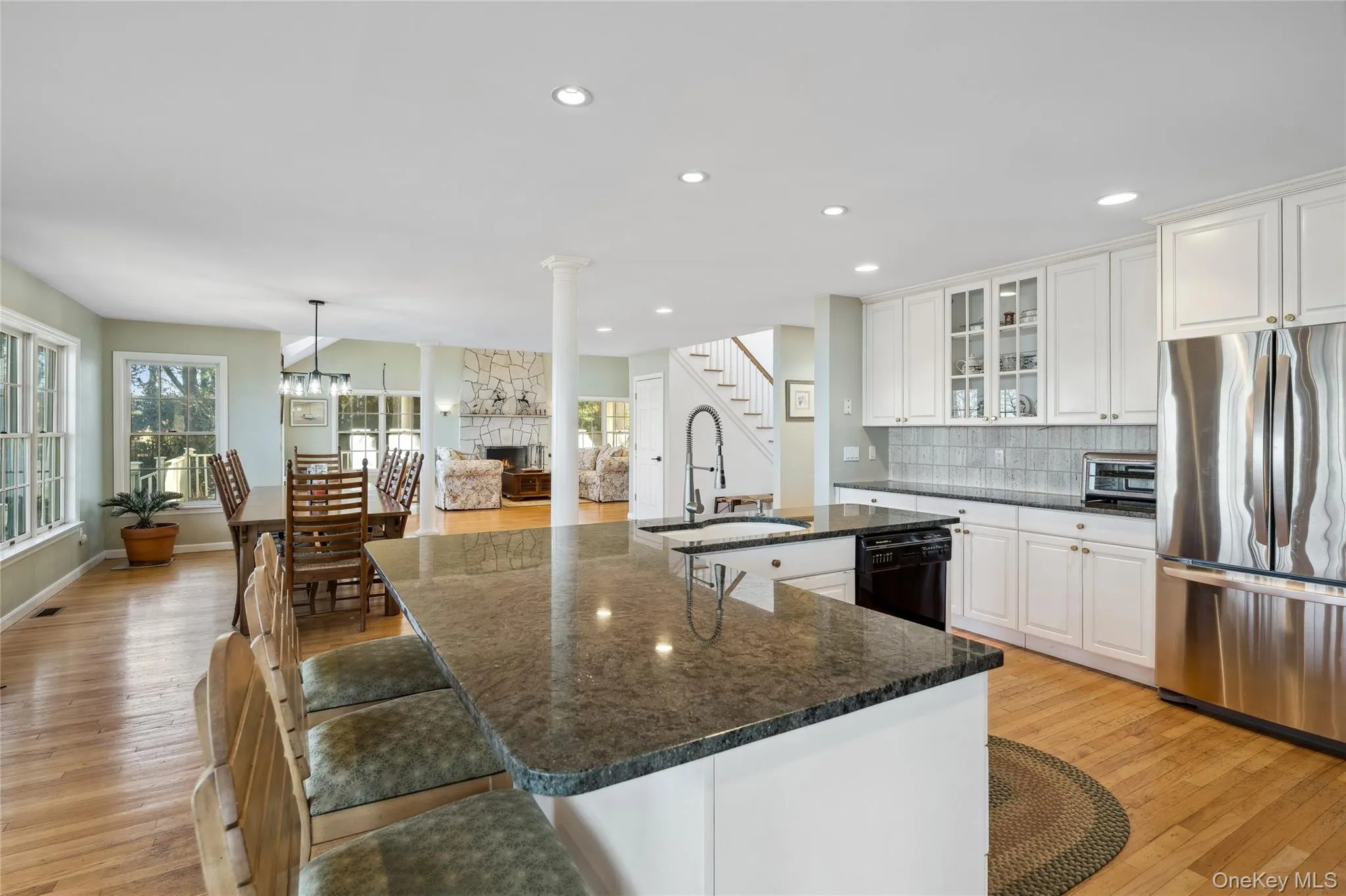 Kitchen featuring a sink, freestanding refrigerator, light wood-style floors, black dishwasher, and a stone fireplace Kitchen featuring a sink, freestanding refrigerator, light wood-style floors, black dishwasher, and a stone fireplace