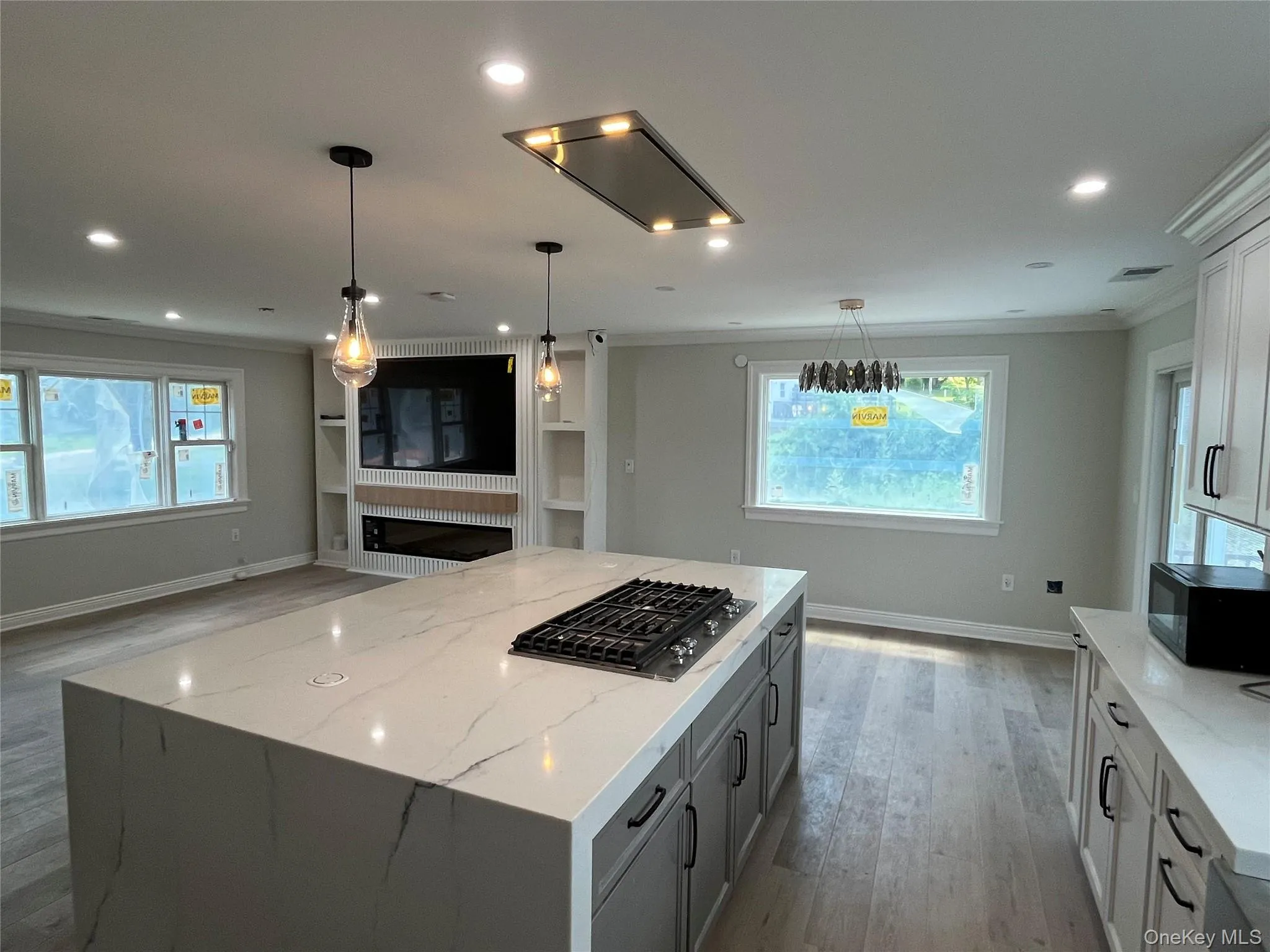 Kitchen with gas stovetop, crown molding, light wood-style floors, black microwave, and light stone counters Kitchen with gas stovetop, crown molding, light wood-style floors, black microwave, and light stone counters