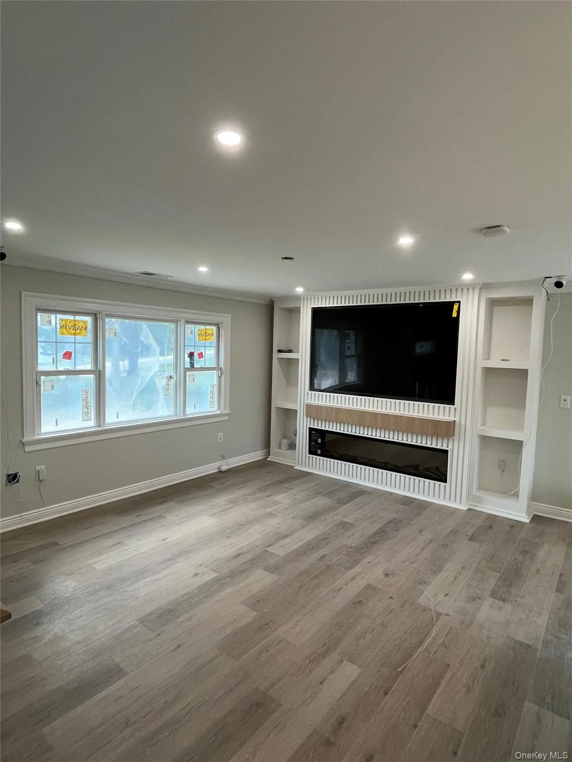 Unfurnished living room with wood finished floors, a fireplace, built in shelves, and recessed lighting Unfurnished living room with wood finished floors, a fireplace, built in shelves, and recessed lighting