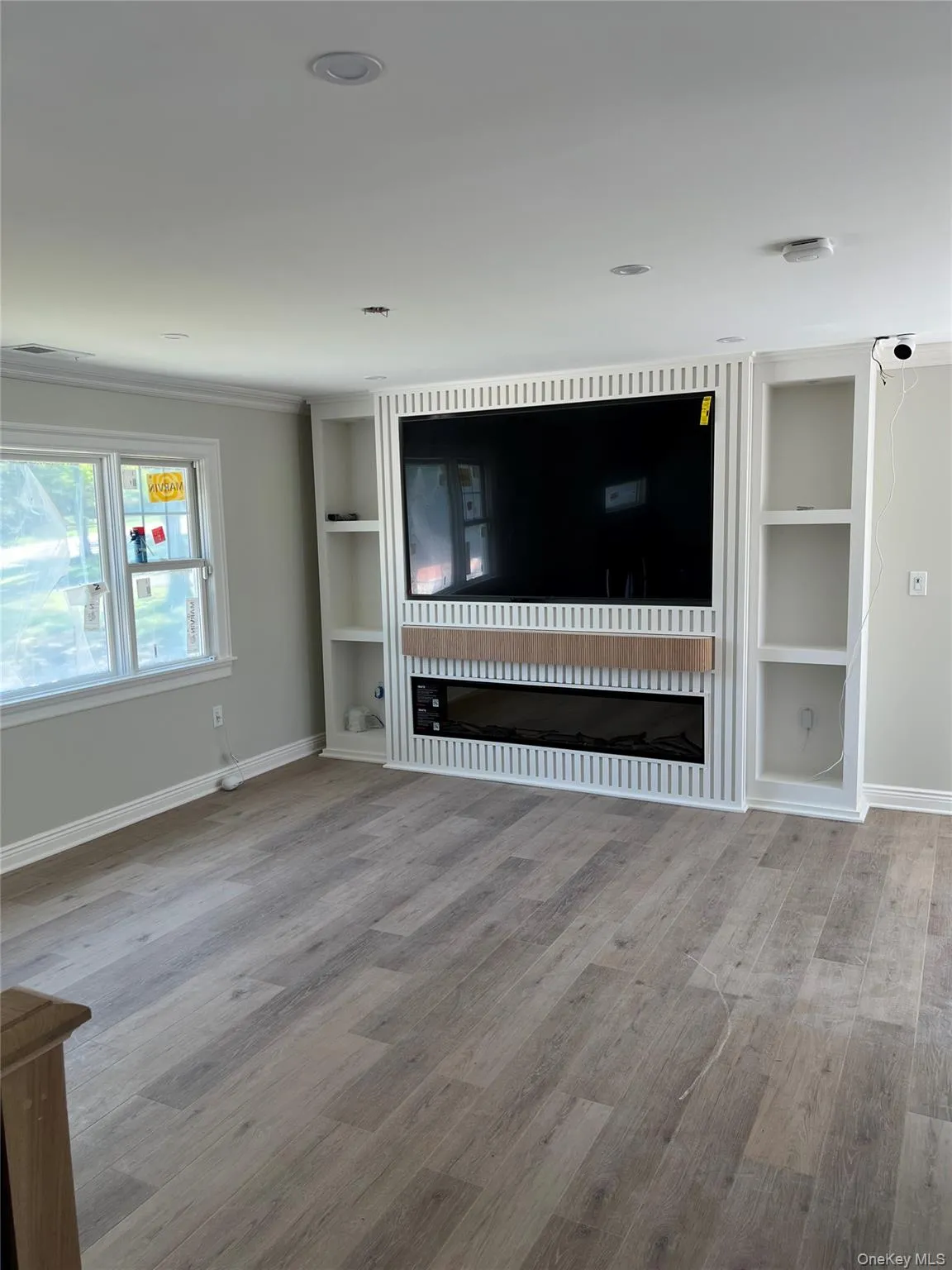 Unfurnished living room with wood finished floors and built in features Unfurnished living room with wood finished floors and built in features